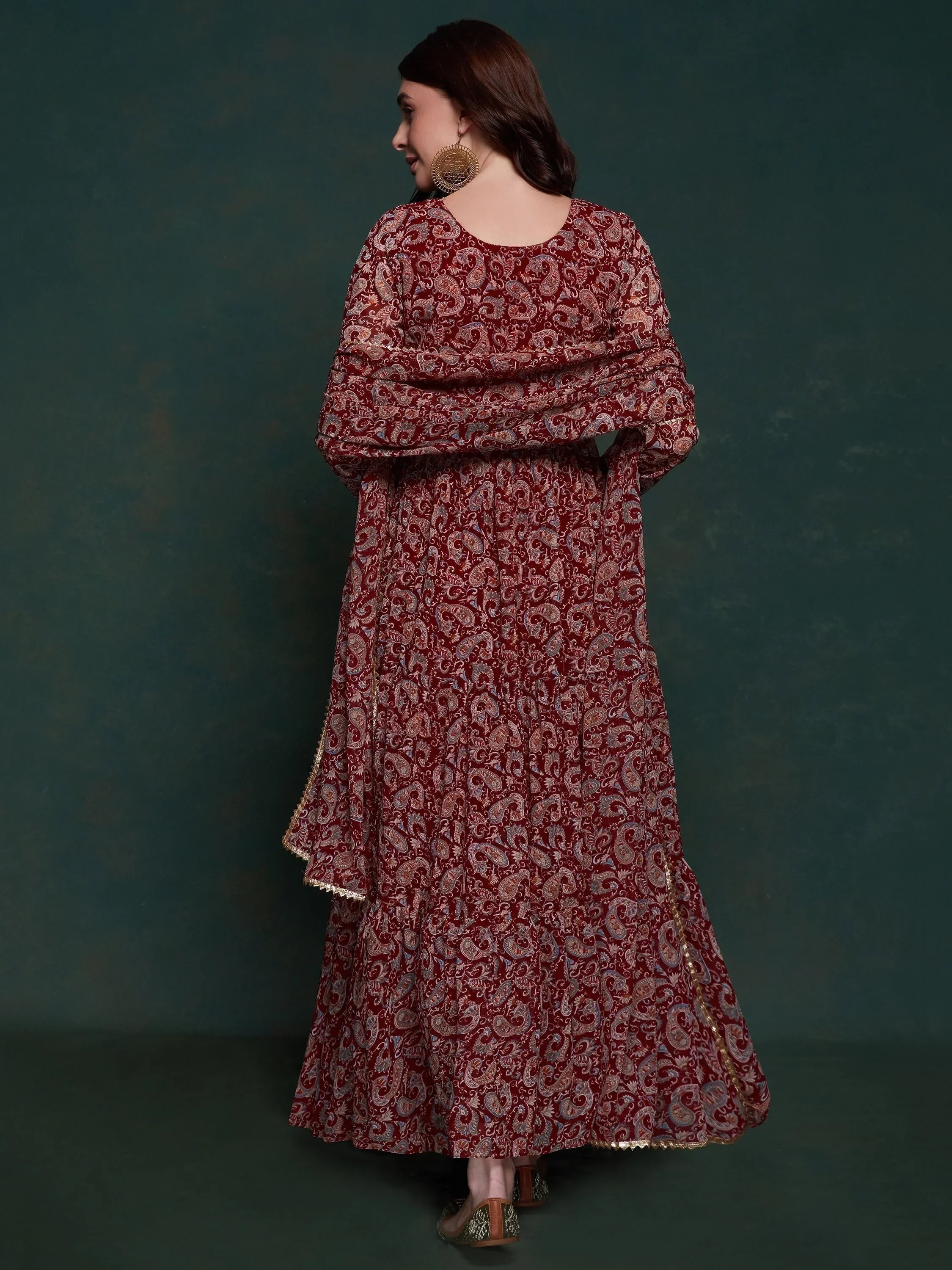 Woman in maroon ethnic gown with gold paisley print and dupatta, back view