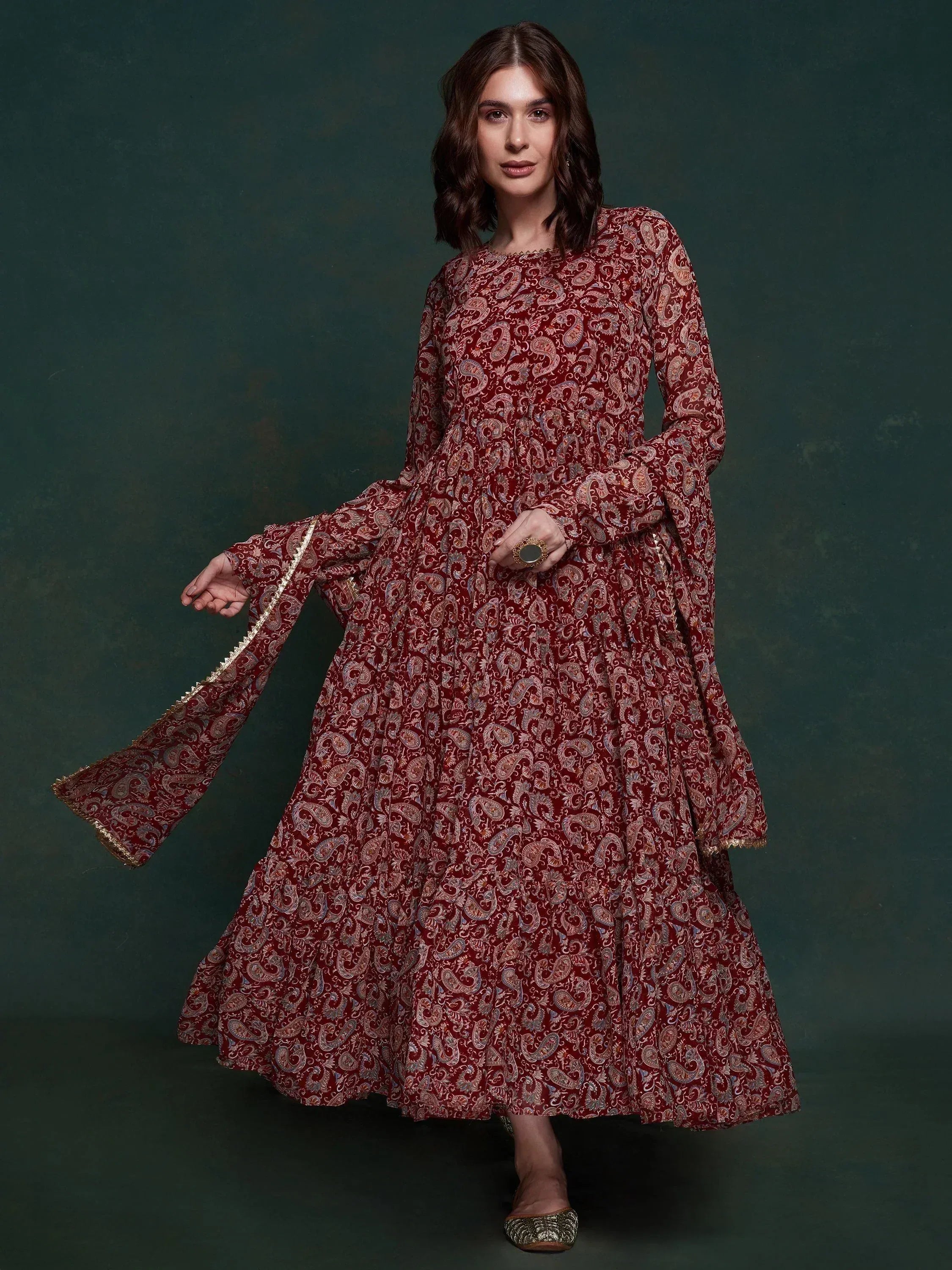 Woman wearing maroon floral printed ethnic gown with long sleeves and flared skirt