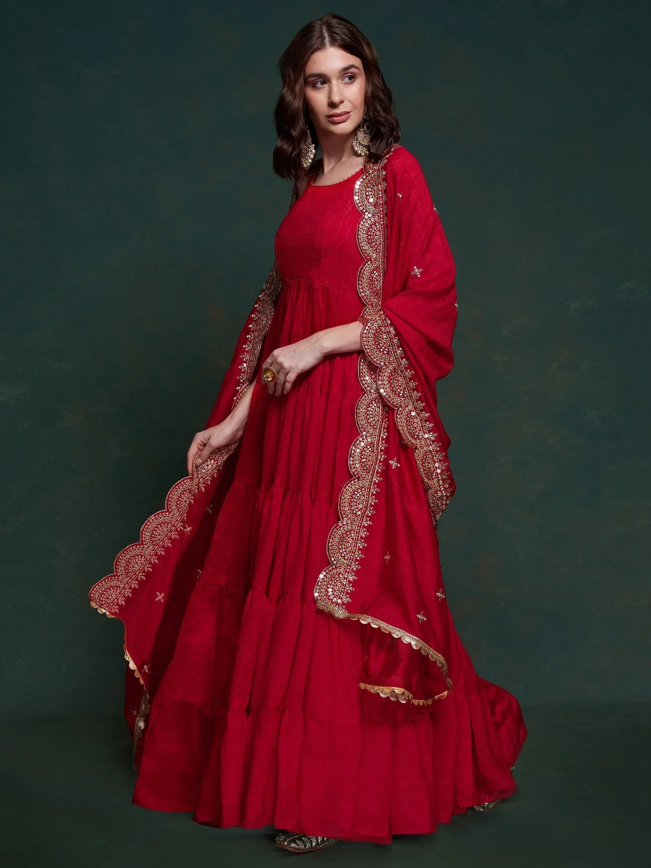 Red ethnic anarkali gown with gold embroidery and mirror work, perfect for Indian weddings and festive occasions.