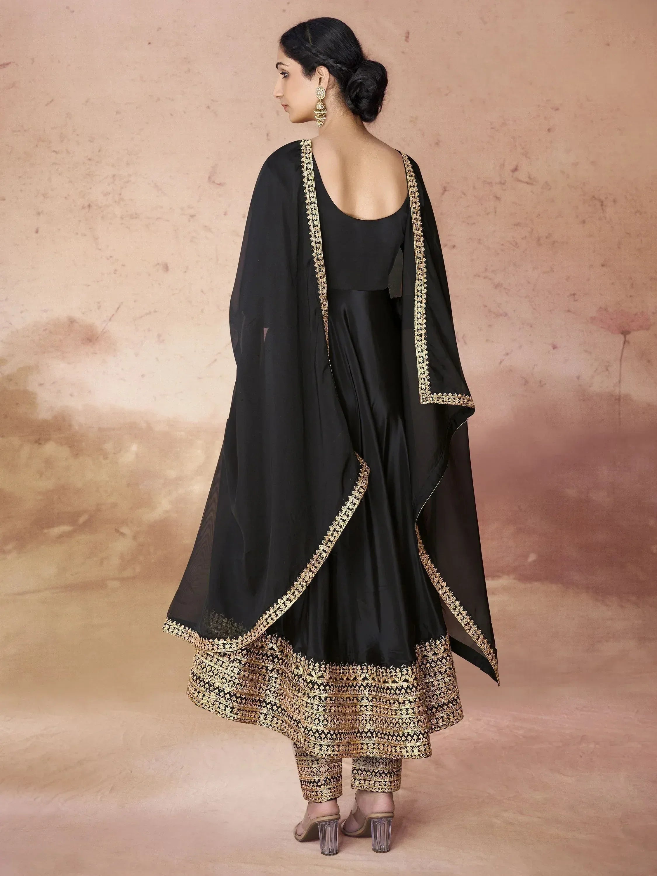 Black ethnic gown with gold embroidery, paired with matching pants and dupatta for festive occasions