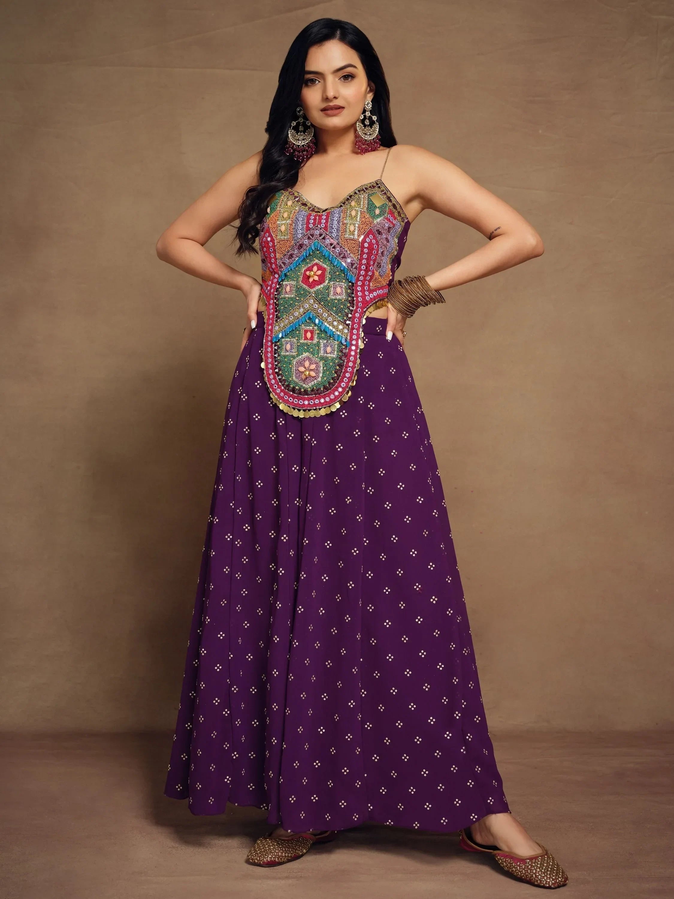 Woman wearing purple ethnic gown with mirror work and embroidered bodice, traditional jewelry