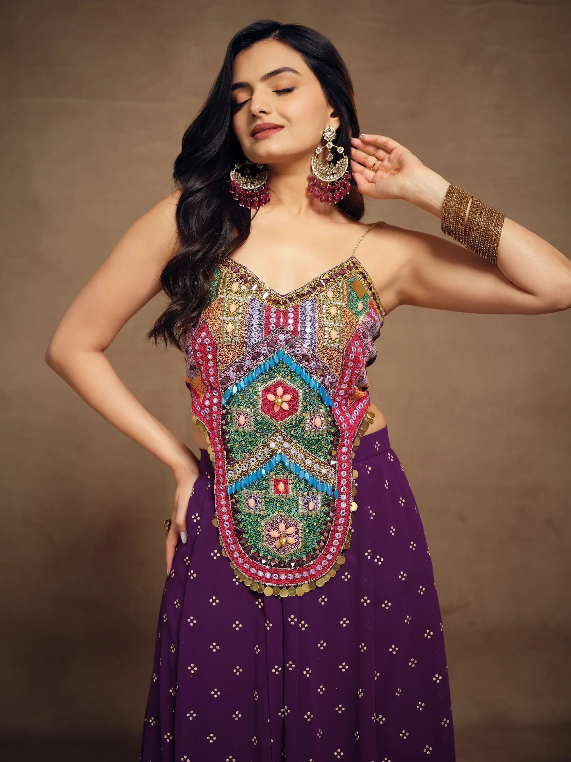 Woman wearing colorful embroidered ethnic top and purple lehenga skirt, festive jewelry