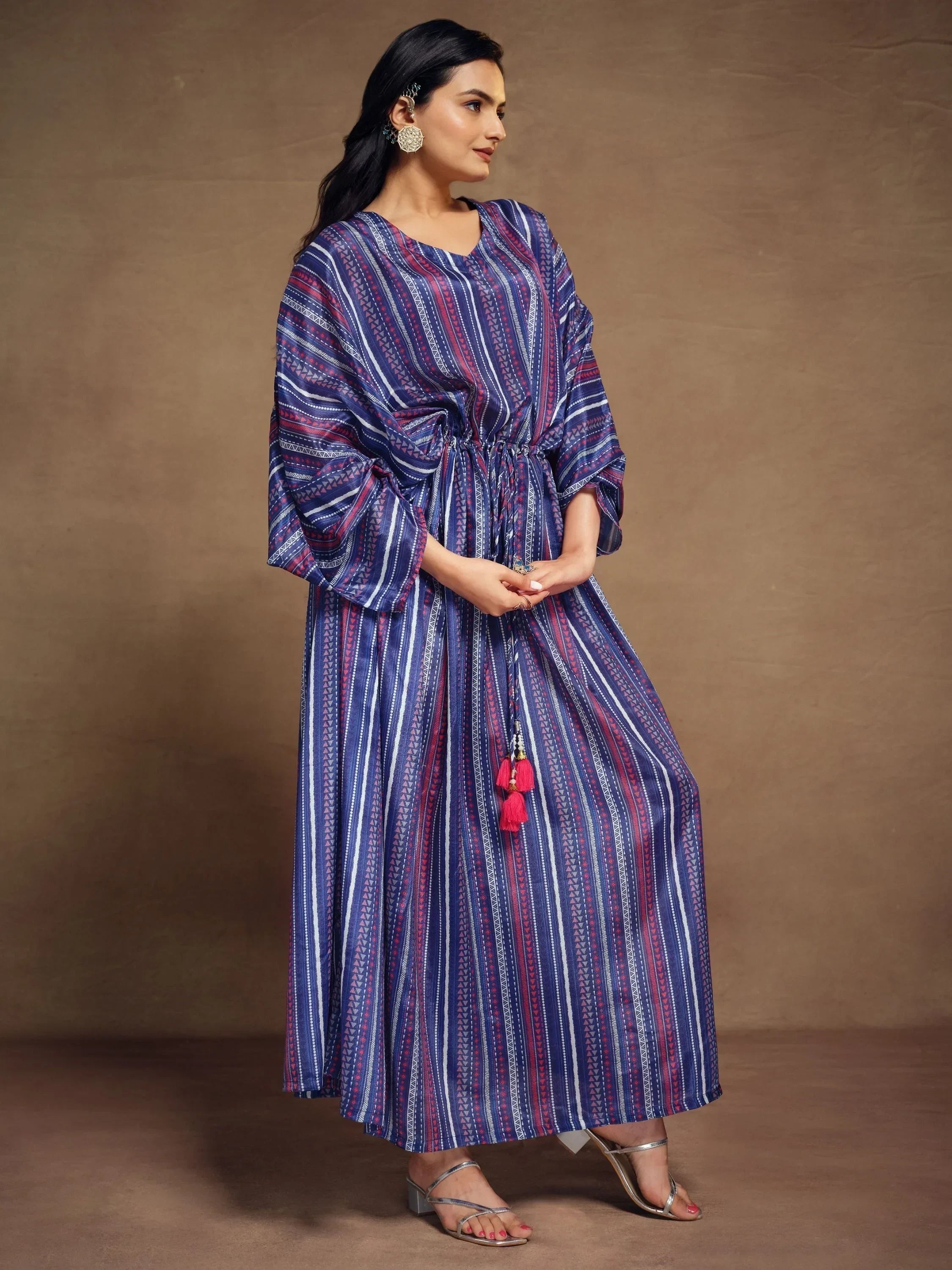 Woman wearing a blue and purple striped kaftan dress with tassel waist tie, ethnic jewelry