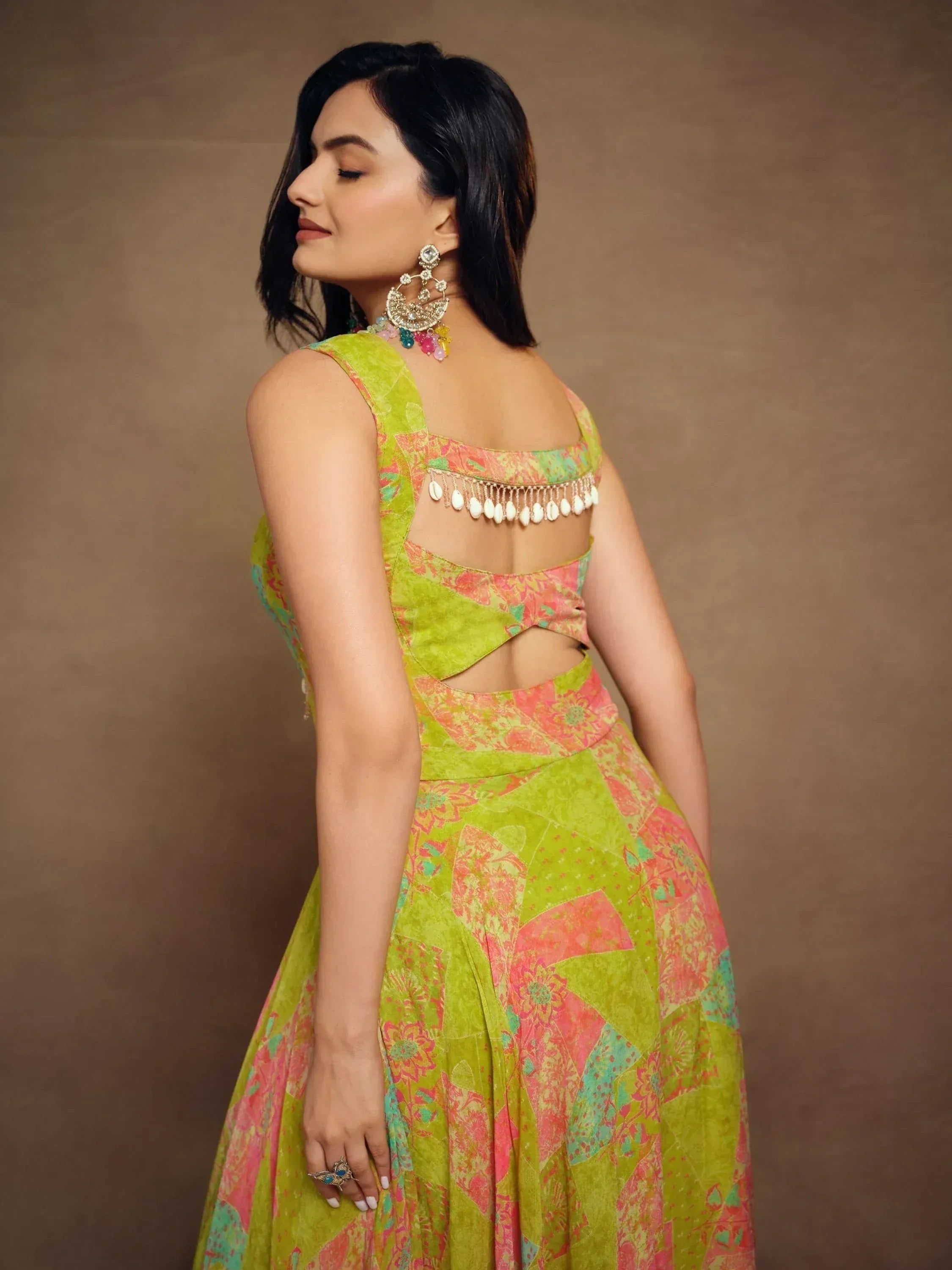 Vibrant green and pink printed lehenga choli with back cutout and shell tassels, styled with statement earrings.