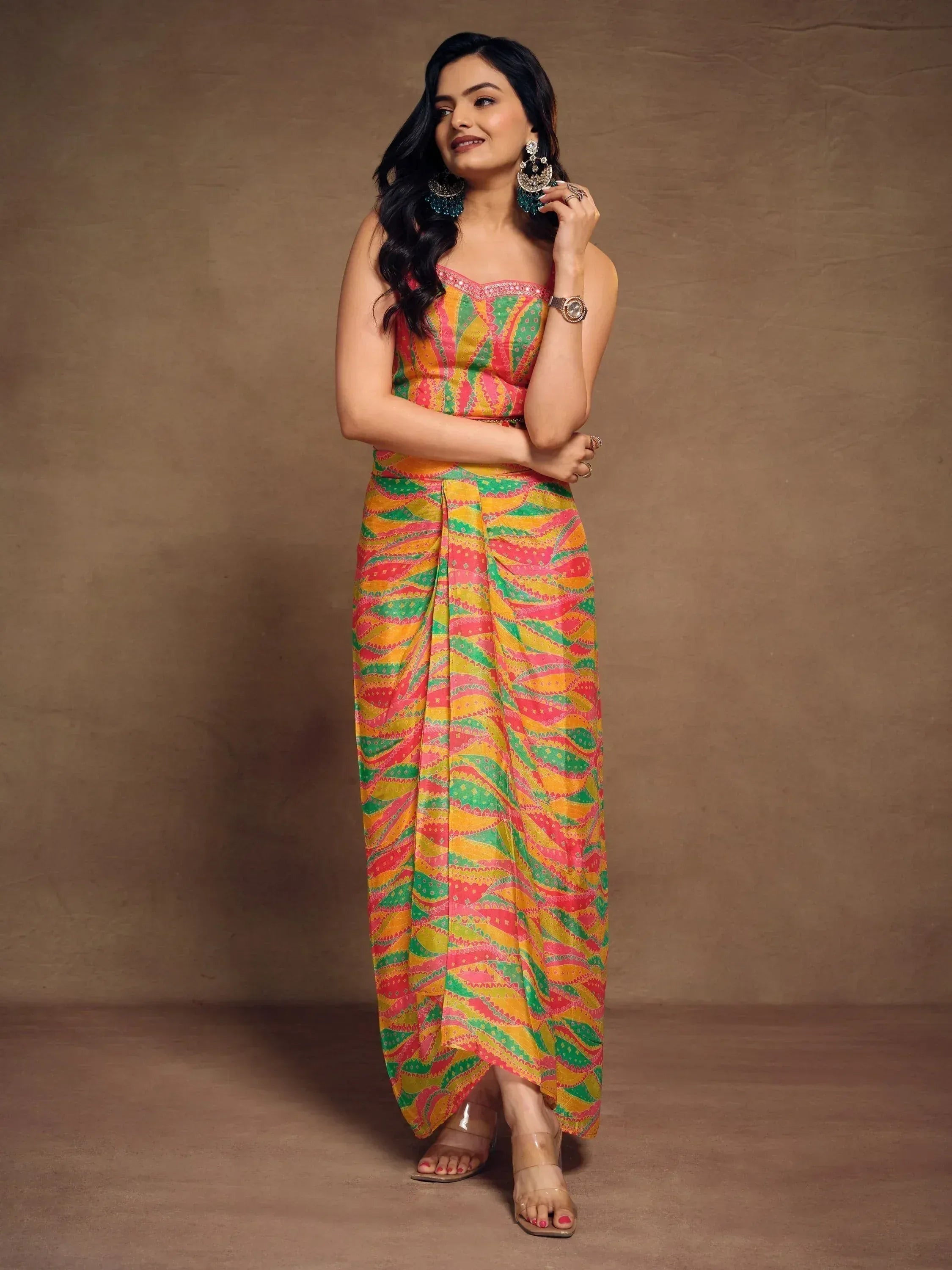Woman in colorful printed ethnic gown with strapless top and draped skirt, styled with statement earrings