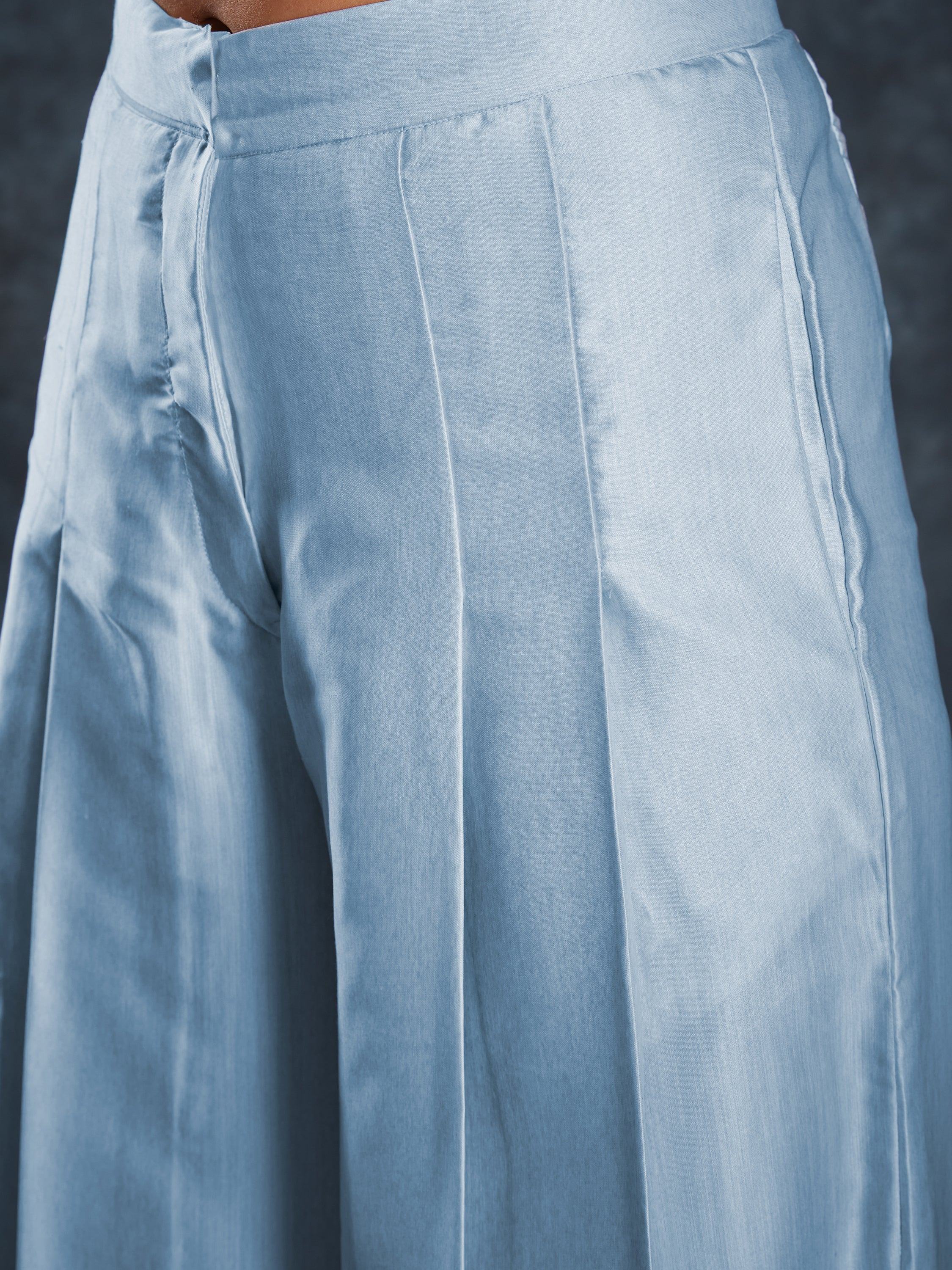 Close-up of light blue pleated palazzo pants with high waist and front seam detailing