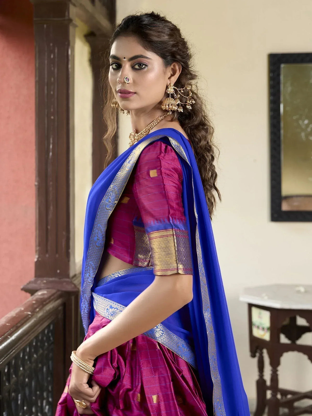 Woman in vibrant purple and blue ethnic saree with gold border, traditional Indian wear