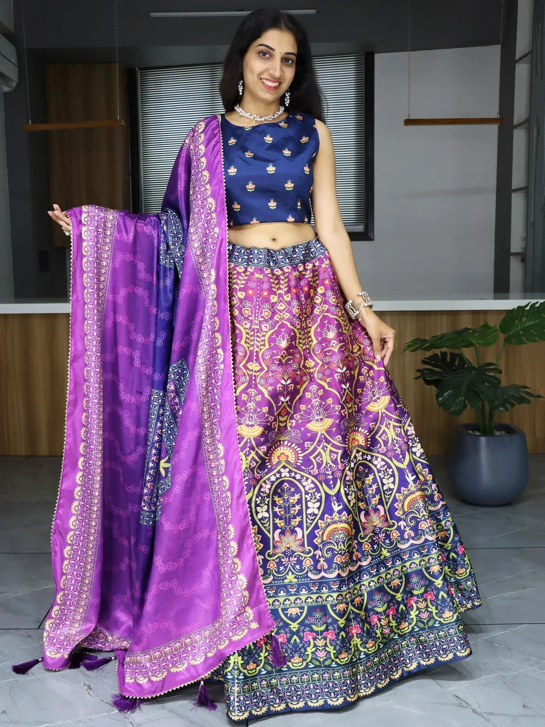 Woman in vibrant purple and blue floral lehenga choli with matching dupatta, showcasing Indian ethnic wear.
