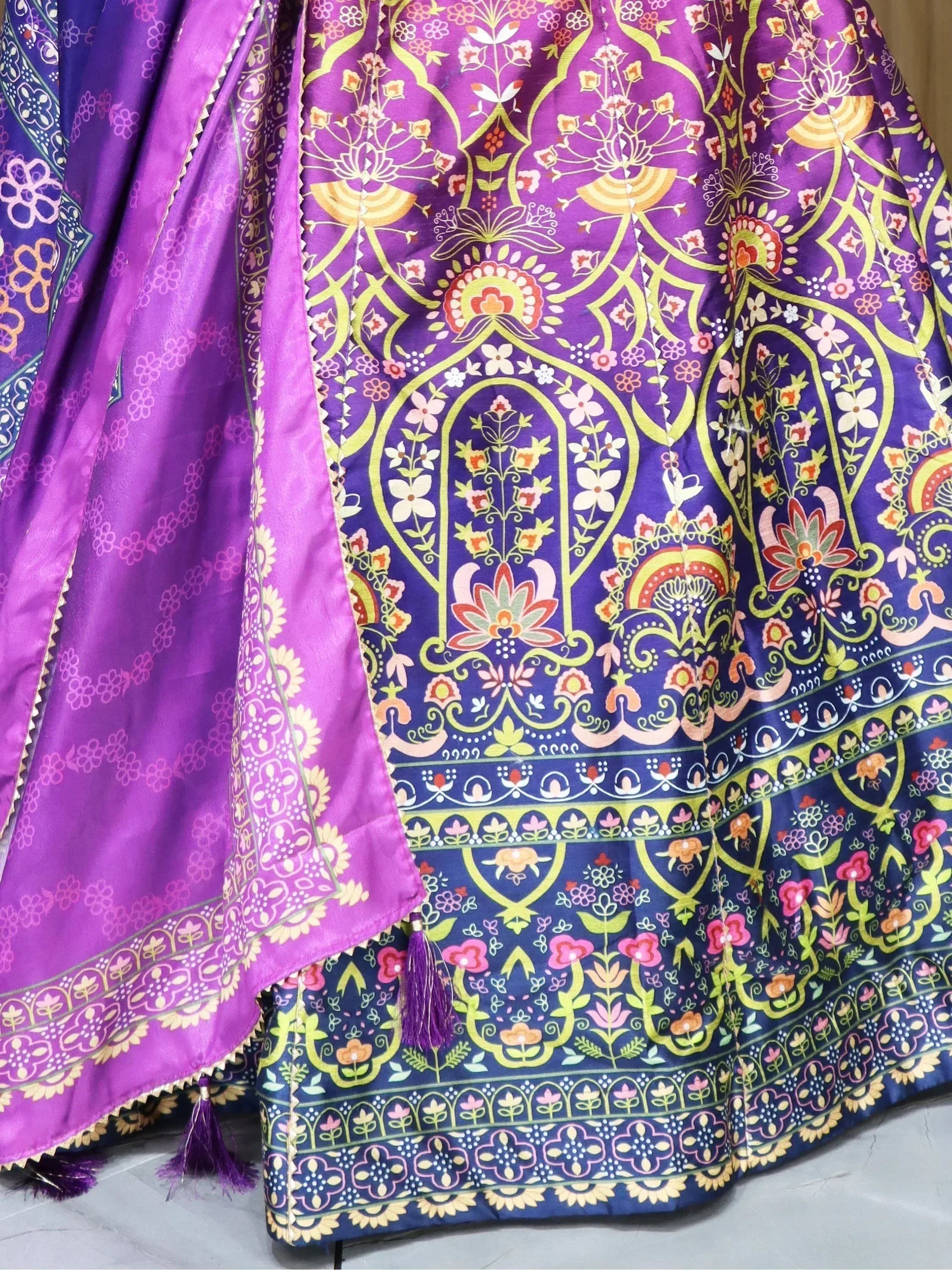 Purple floral print lehenga choli with intricate patterns and tassels, ideal for Indian ethnic wear.