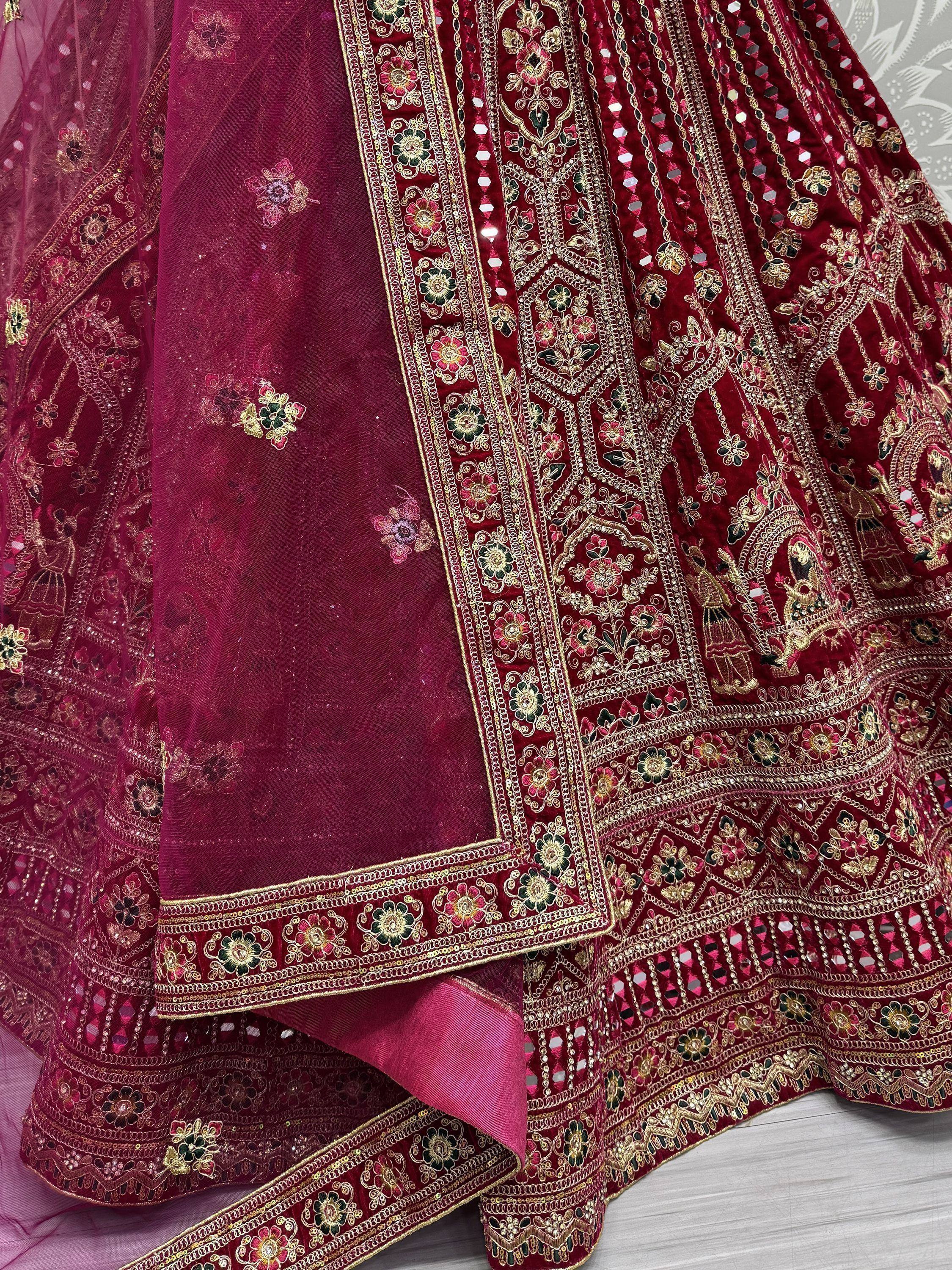 Luxury maroon velvet lehenga choli with intricate gold embroidery and mirror work, perfect for Indian weddings.