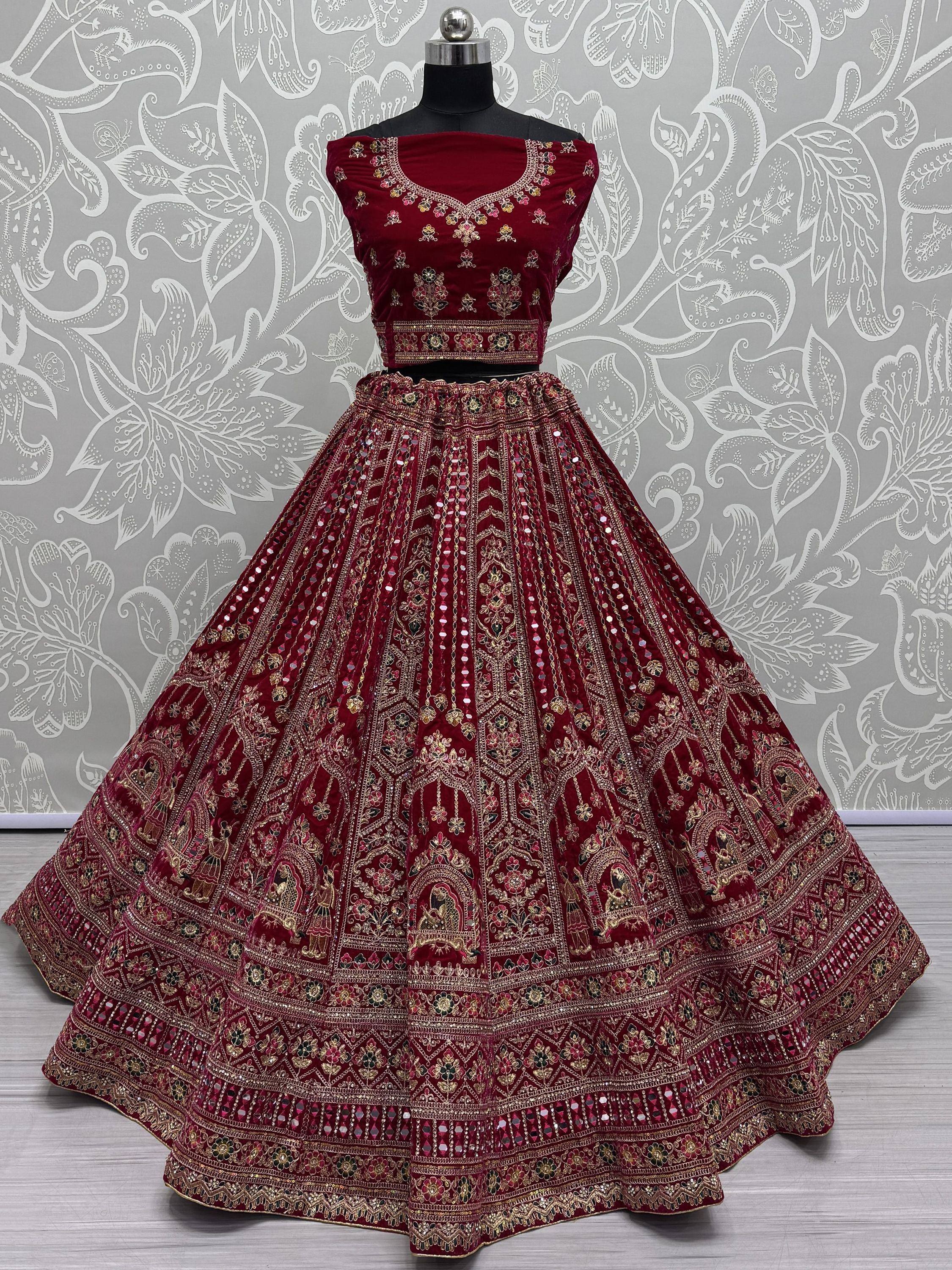 Maroon velvet lehenga choli with heavy gold embroidery and mirror work, displayed on mannequin