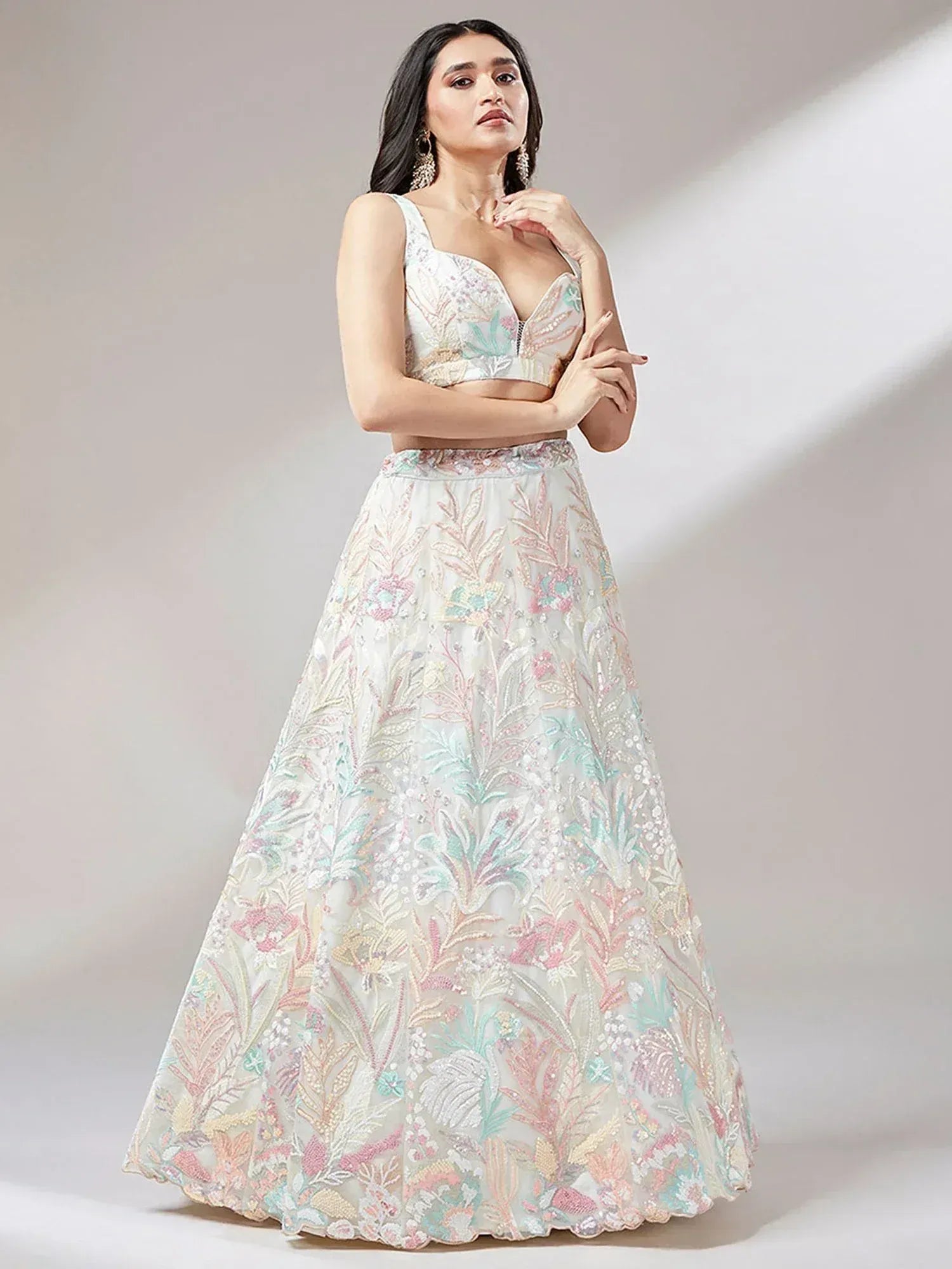 Elegant white lehenga choli with pastel floral embroidery, perfect for Indian ethnic occasions.