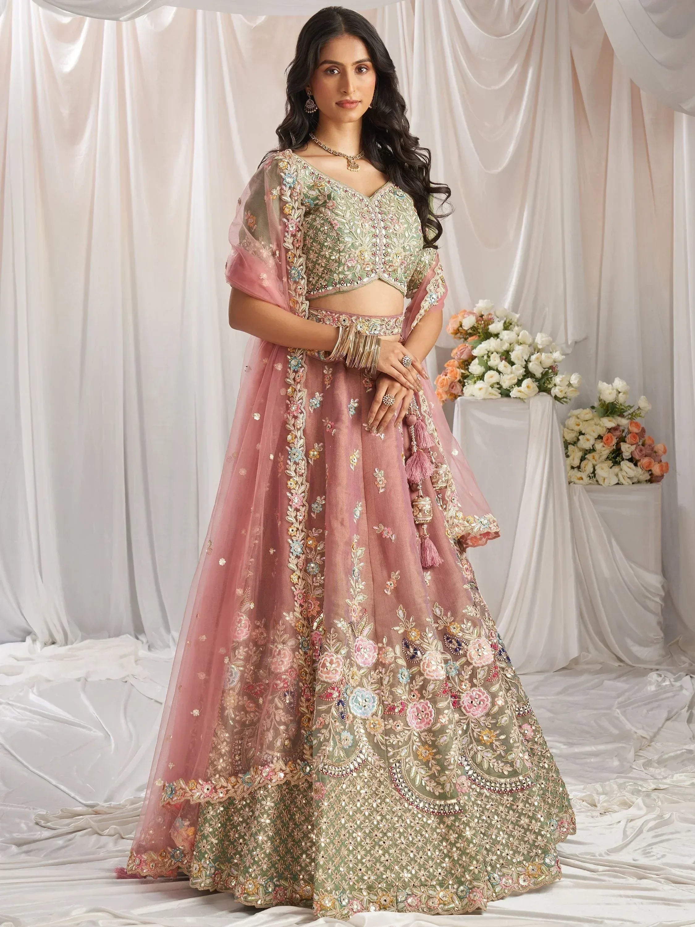 Pink and green embroidered lehenga choli with floral motifs, perfect for Indian weddings and festive occasions.