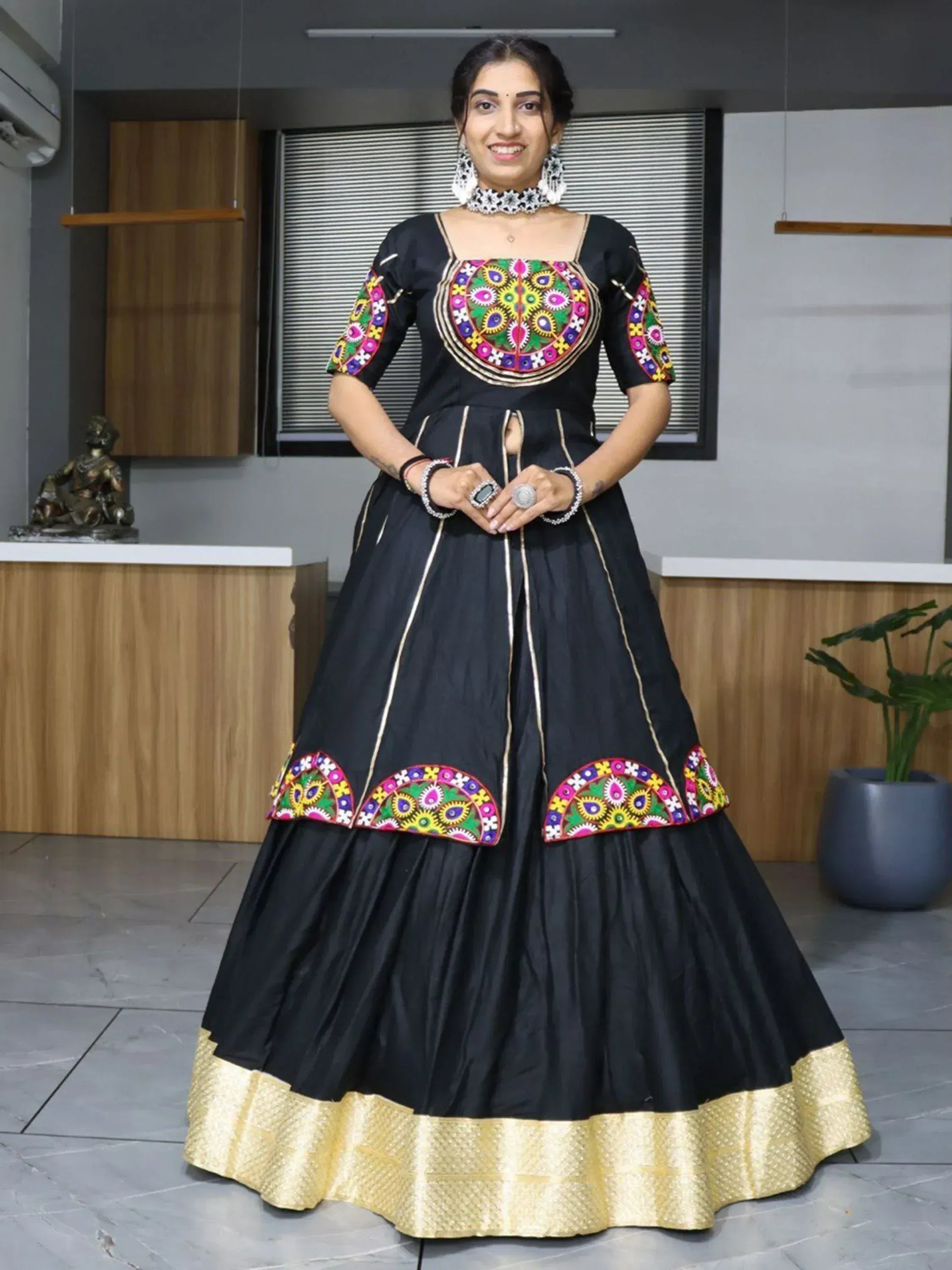 Black ethnic gown with colorful mirror work and gold border, perfect for Indian occasions
