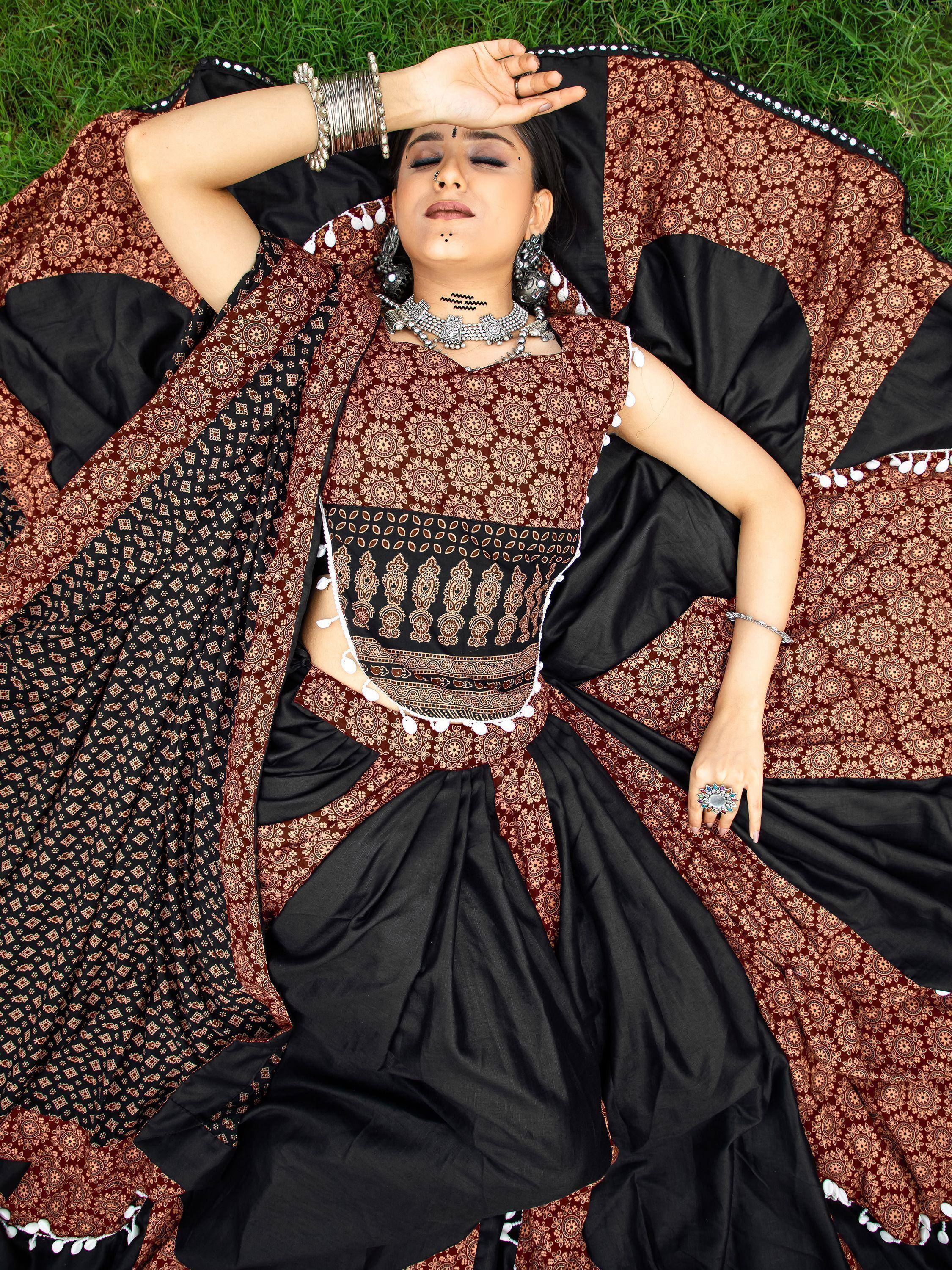 Woman in black and maroon printed ethnic lehenga choli with silver jewelry, lying on grass