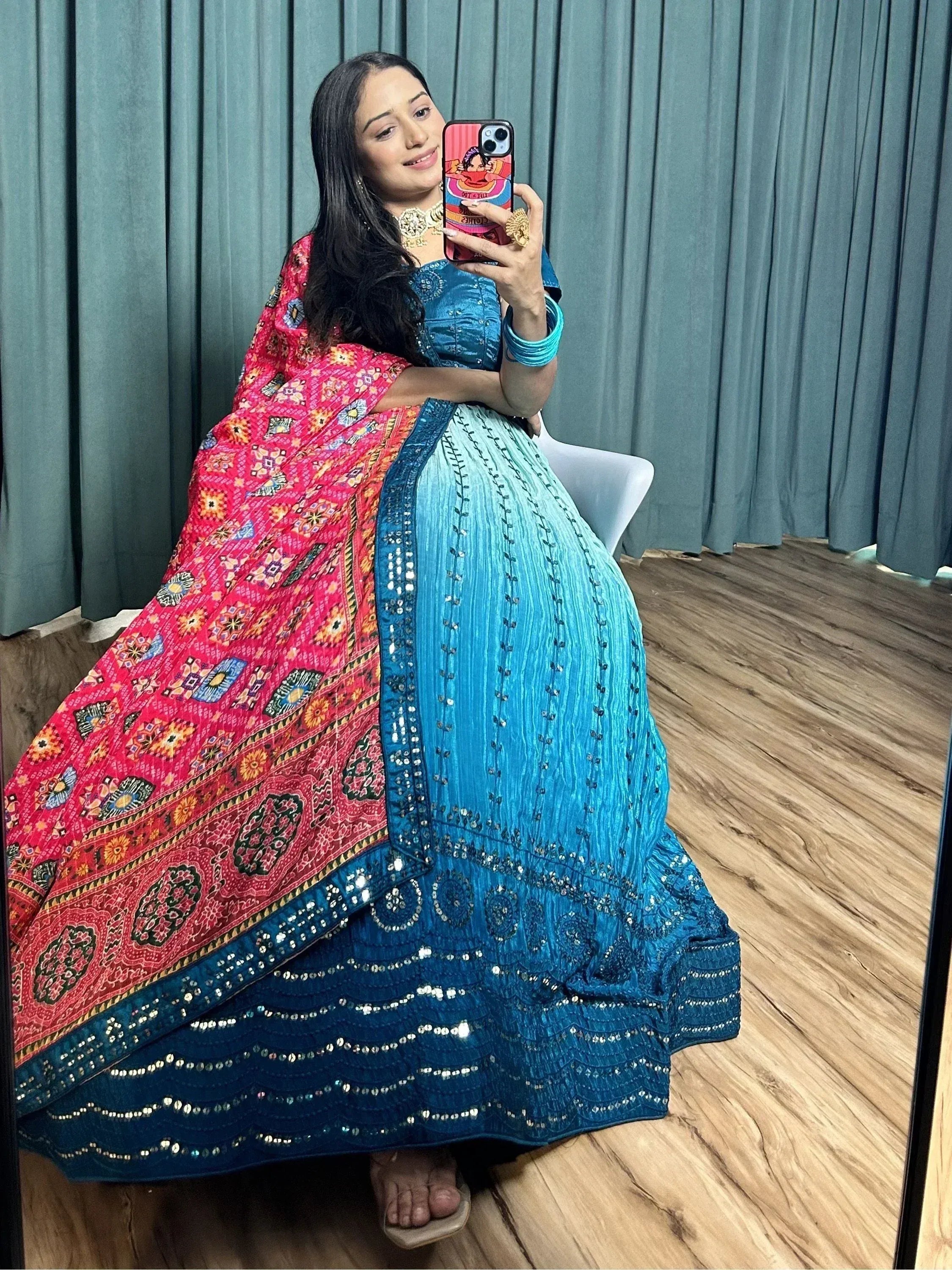 Woman in blue lehenga choli with pink embroidered dupatta, taking mirror selfie, ethnic wear