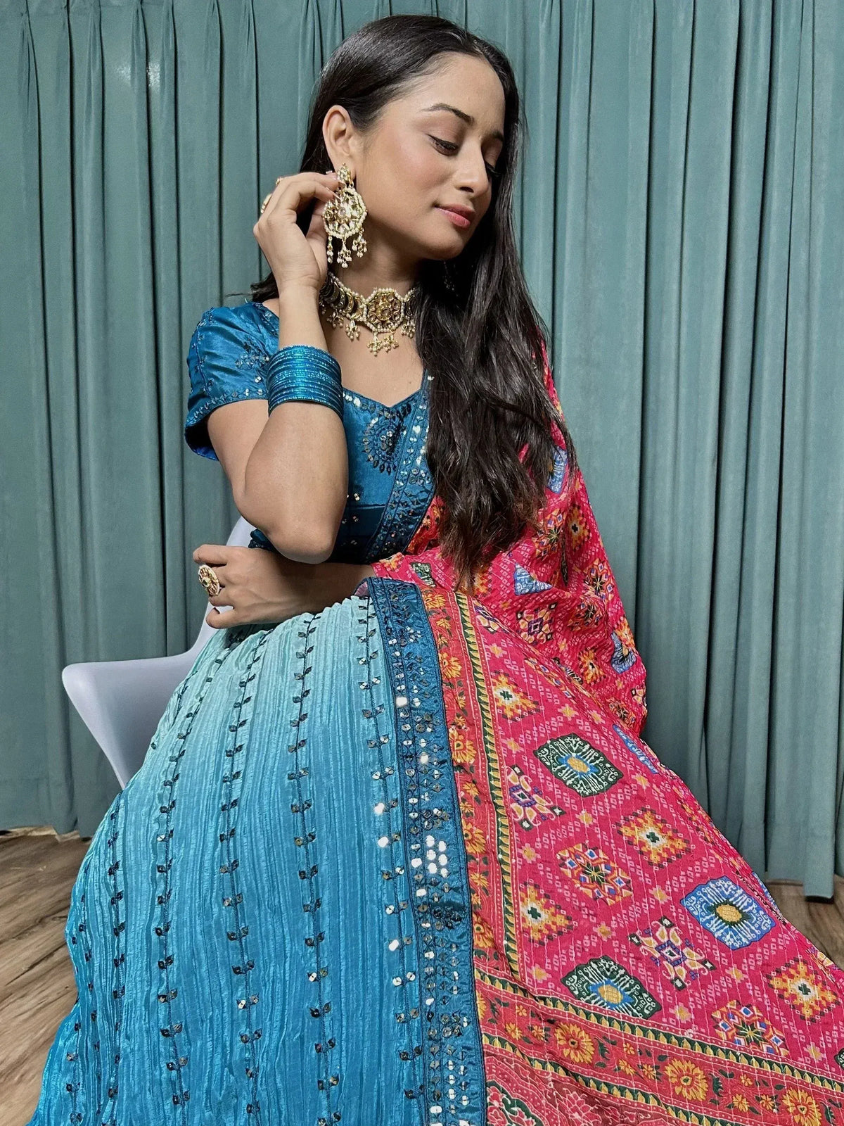 Woman in blue sequined lehenga choli with red printed dupatta, gold jewelry, ethnic Indian wear