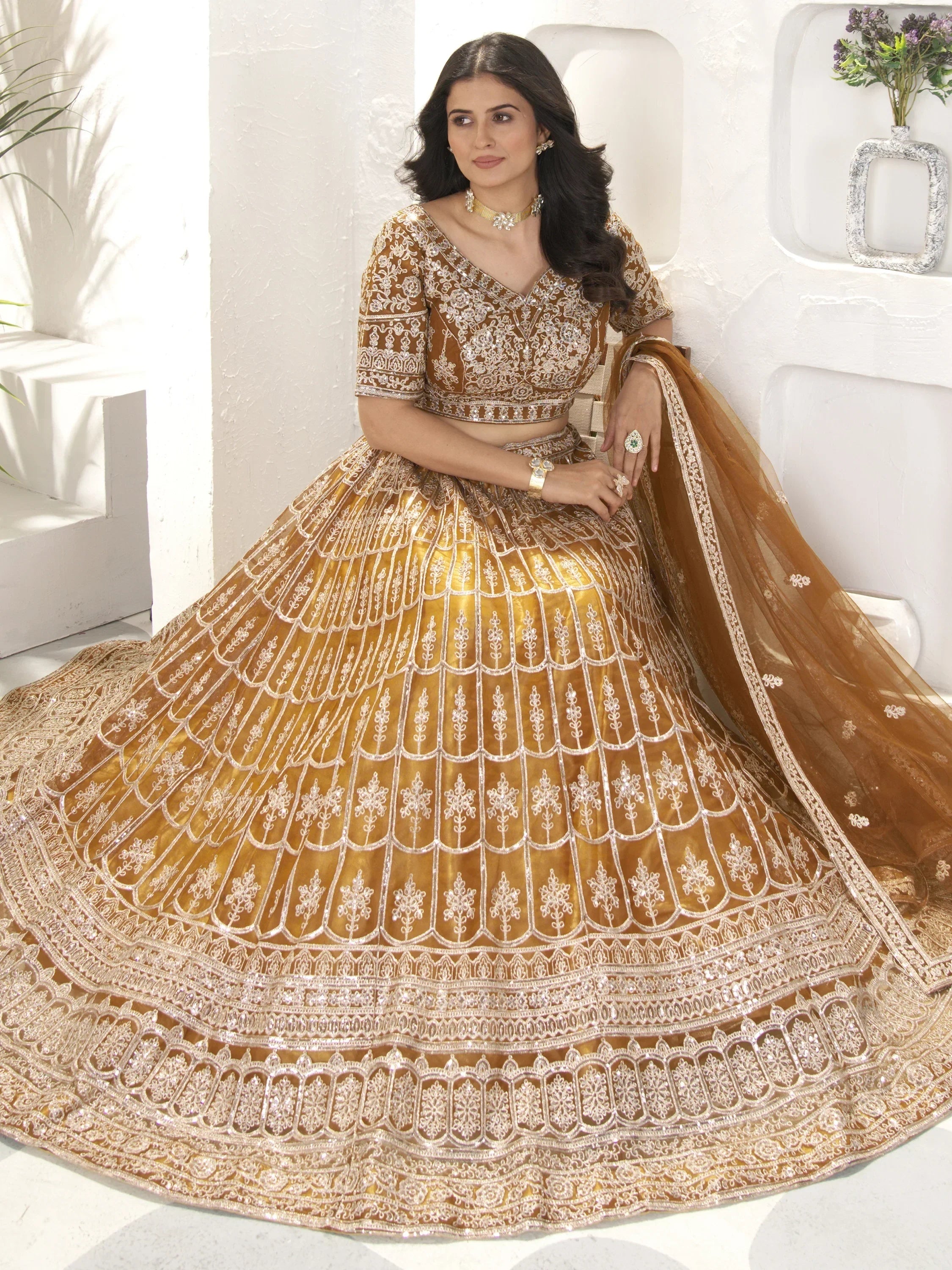 Golden designer lehenga choli with intricate embroidery and scalloped skirt, perfect for Indian weddings and festive occasions.