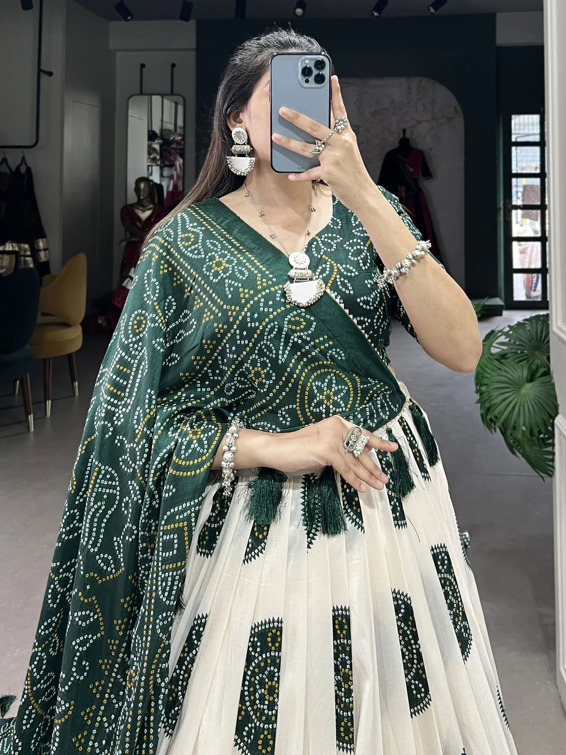 Green and cream printed lehenga choli with tassels, paired with silver jewelry for ethnic wear