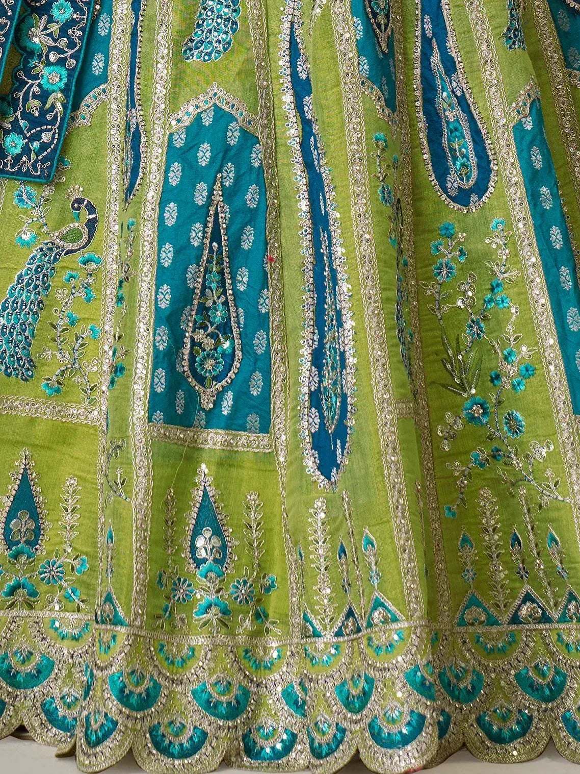 Green and teal embroidered lehenga with peacock motifs and gold detailing, perfect for Indian ethnic wear.
