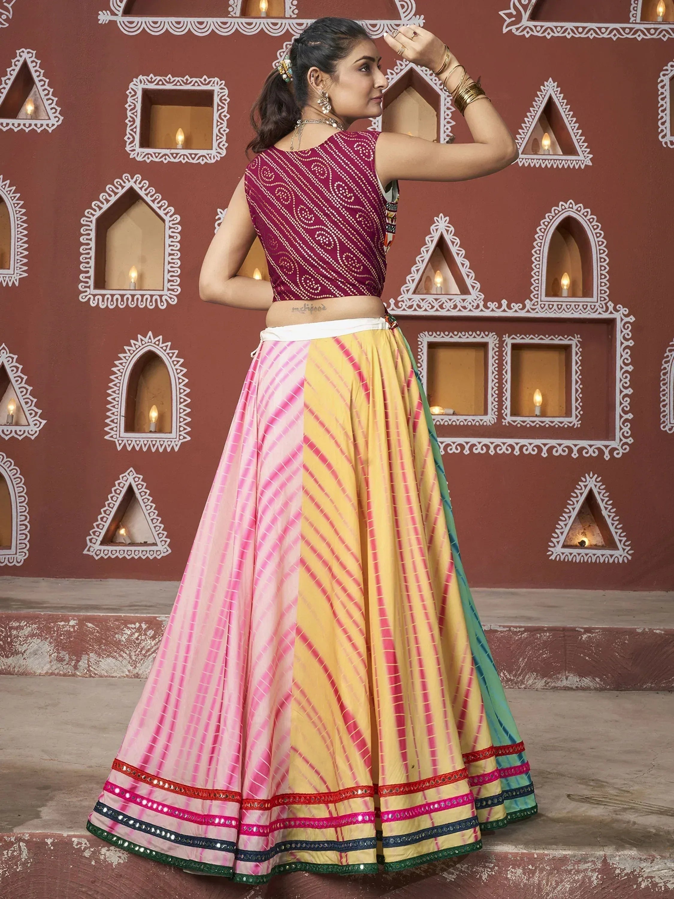 Woman in colorful Indian lehenga choli with pink yellow skirt and embroidered border, traditional ethnic wear