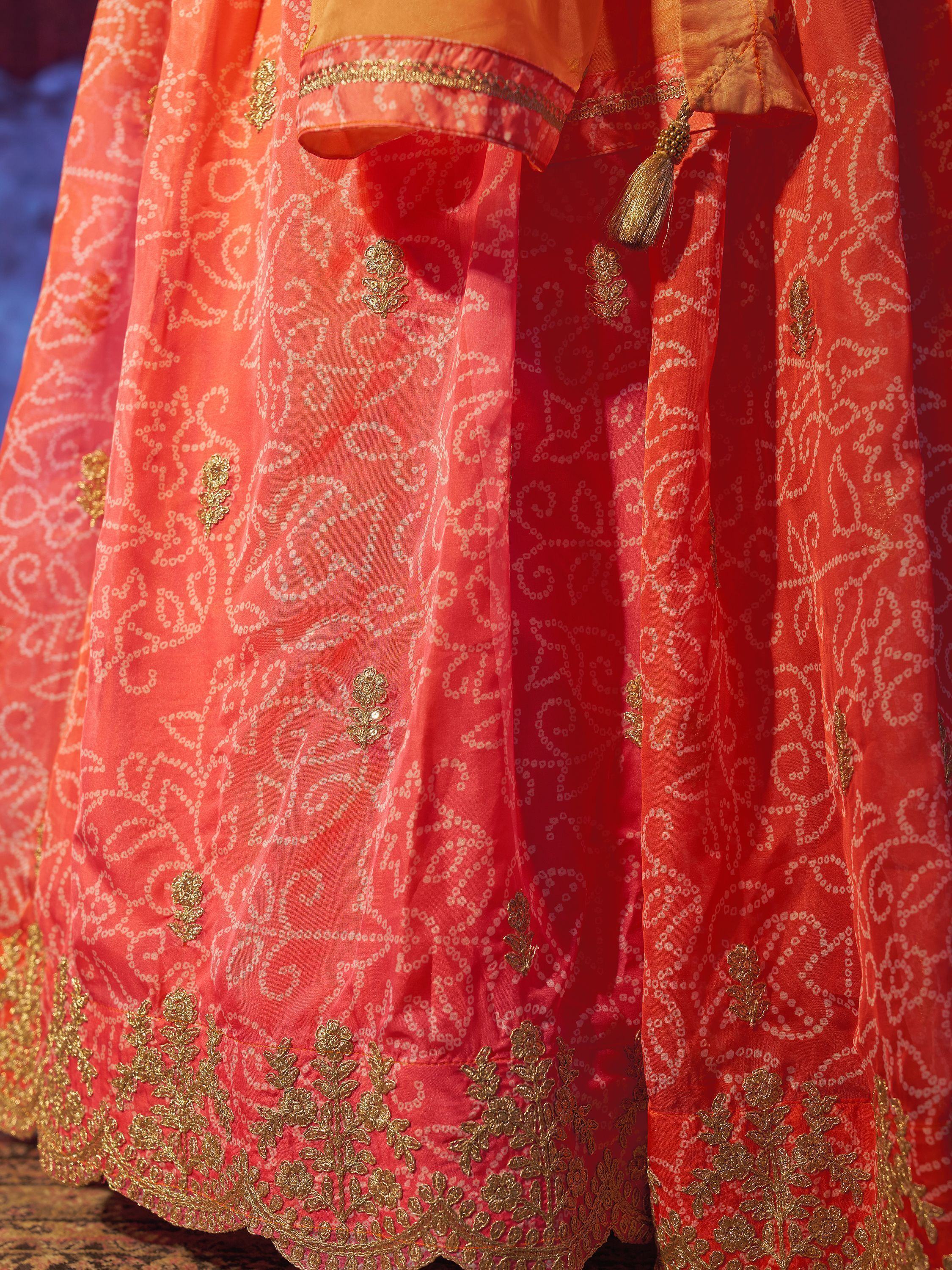 Orange Indian ethnic lehenga with gold embroidery and floral motifs, perfect for festive occasions.