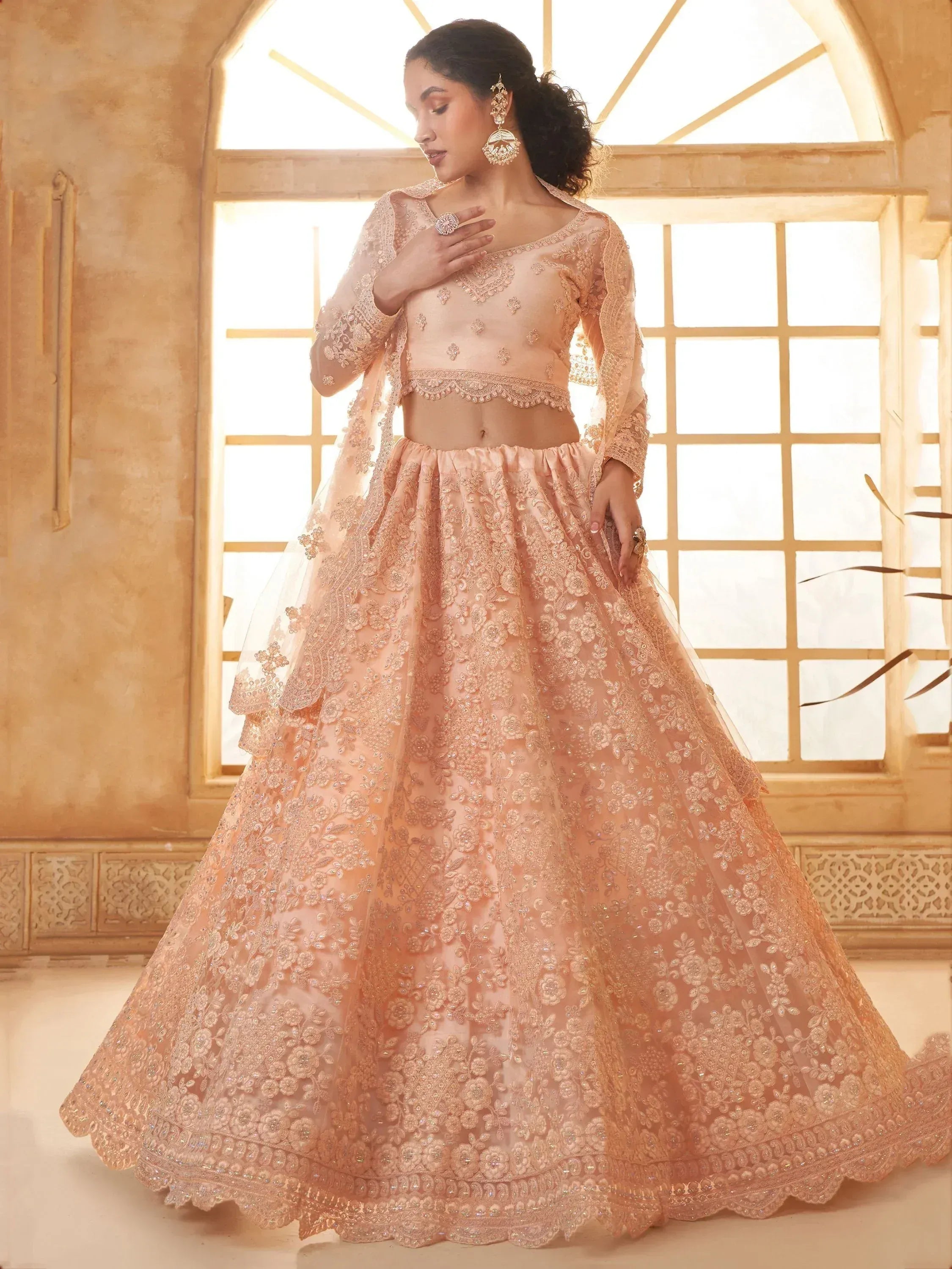 Elegant peach lehenga choli with intricate floral embroidery and sheer dupatta, perfect for Indian weddings or festive occasions.