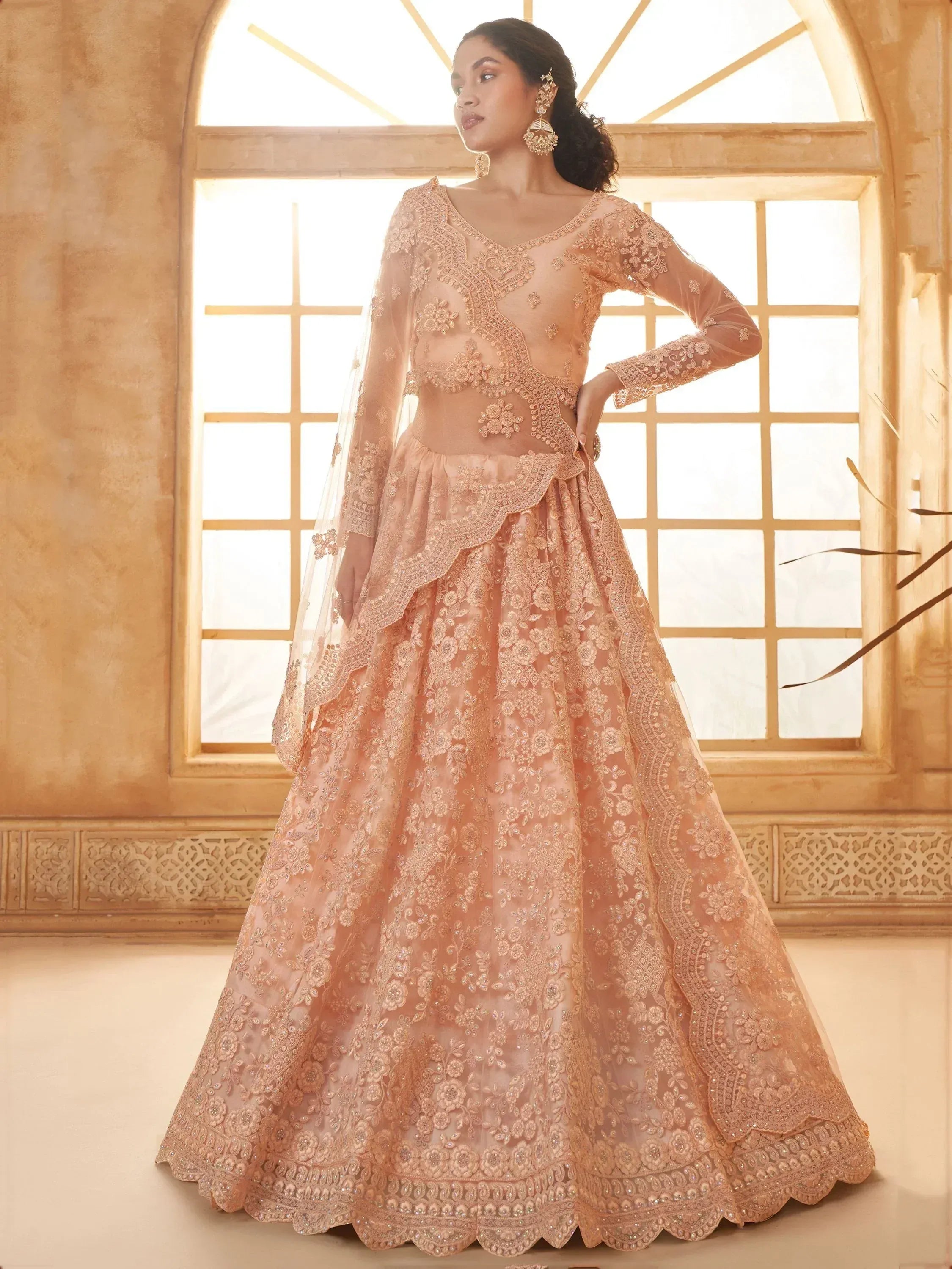 Elegant peach designer lehenga choli with intricate floral embroidery and sheer dupatta, perfect for Indian weddings.