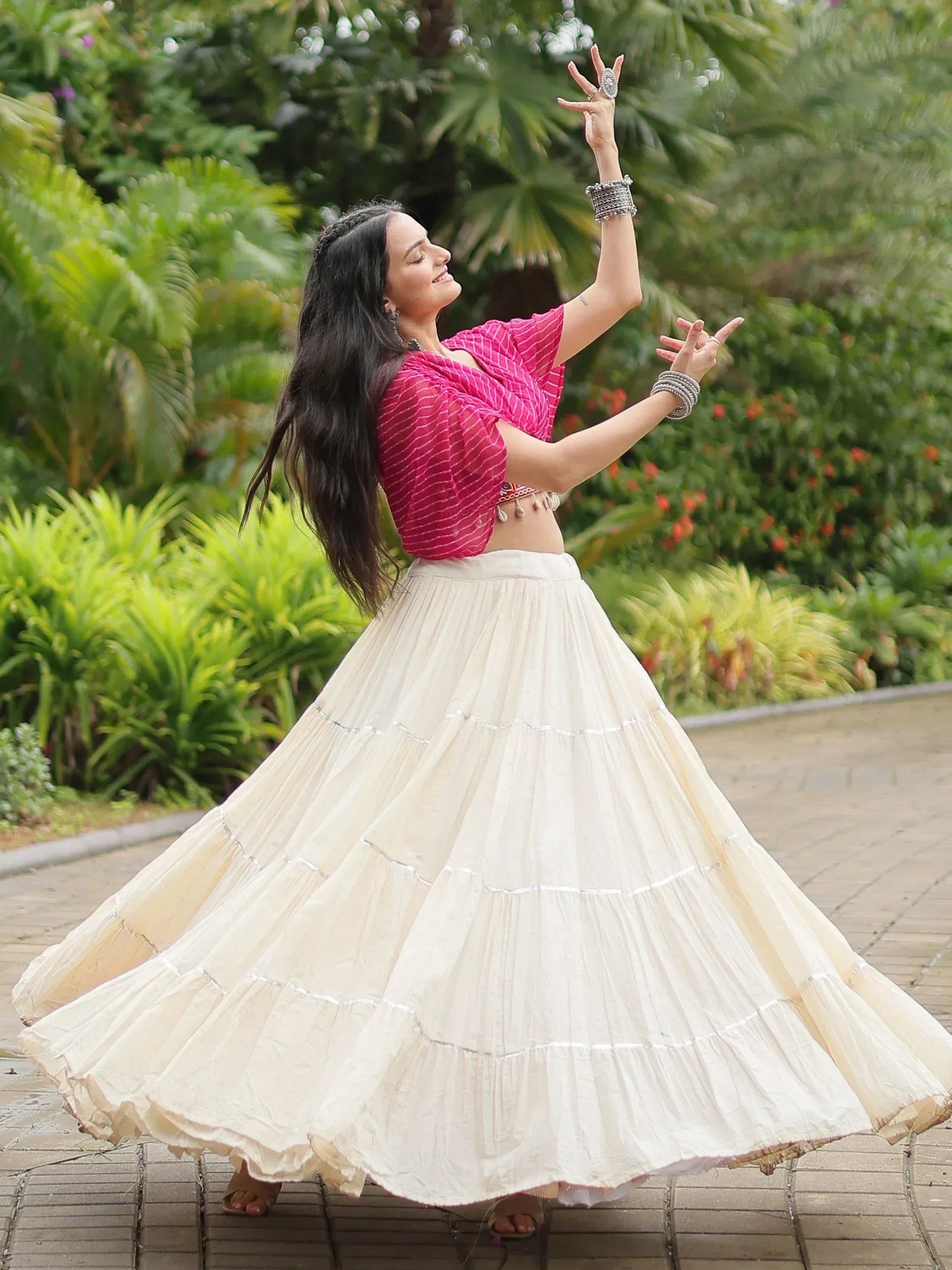 Woman dancing in pink striped blouse and cream pleated skirt, ethnic wear for festive occasions