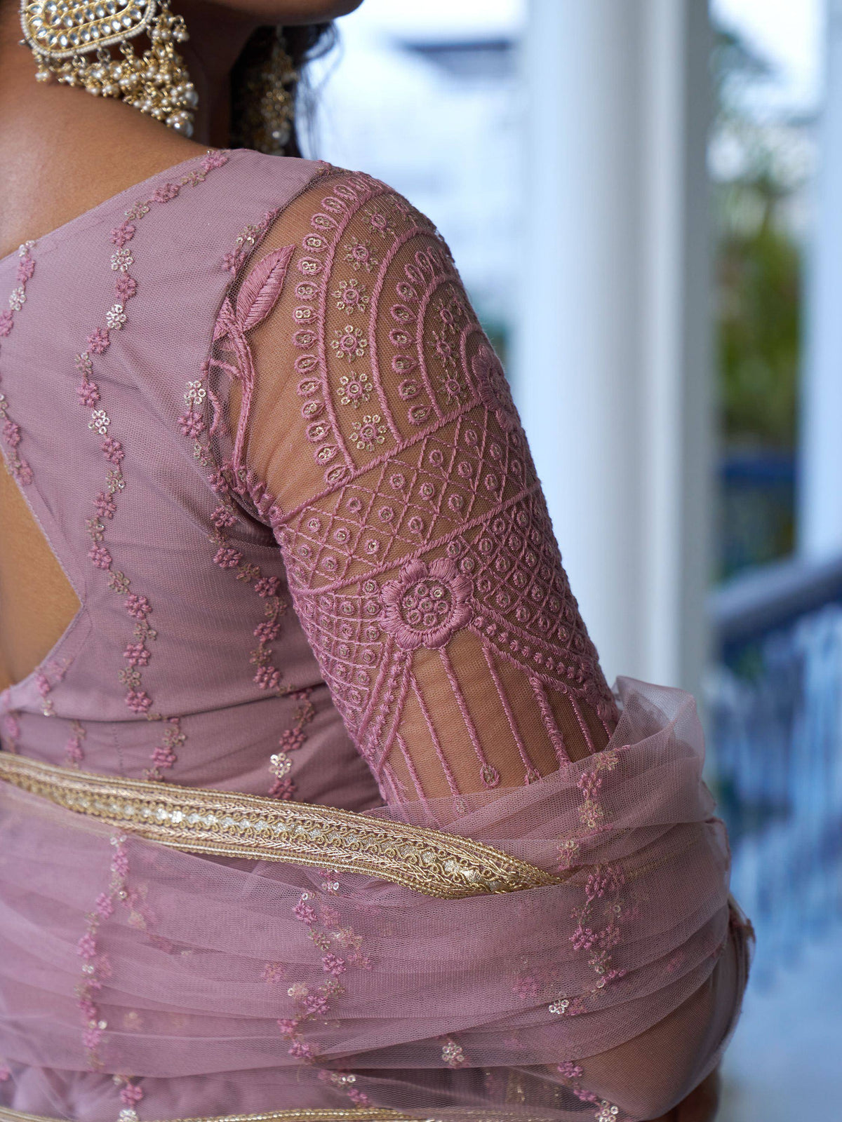 Dusty pink embroidered lehenga choli with sheer sleeves and gold detailing, perfect for Indian ethnic wear.