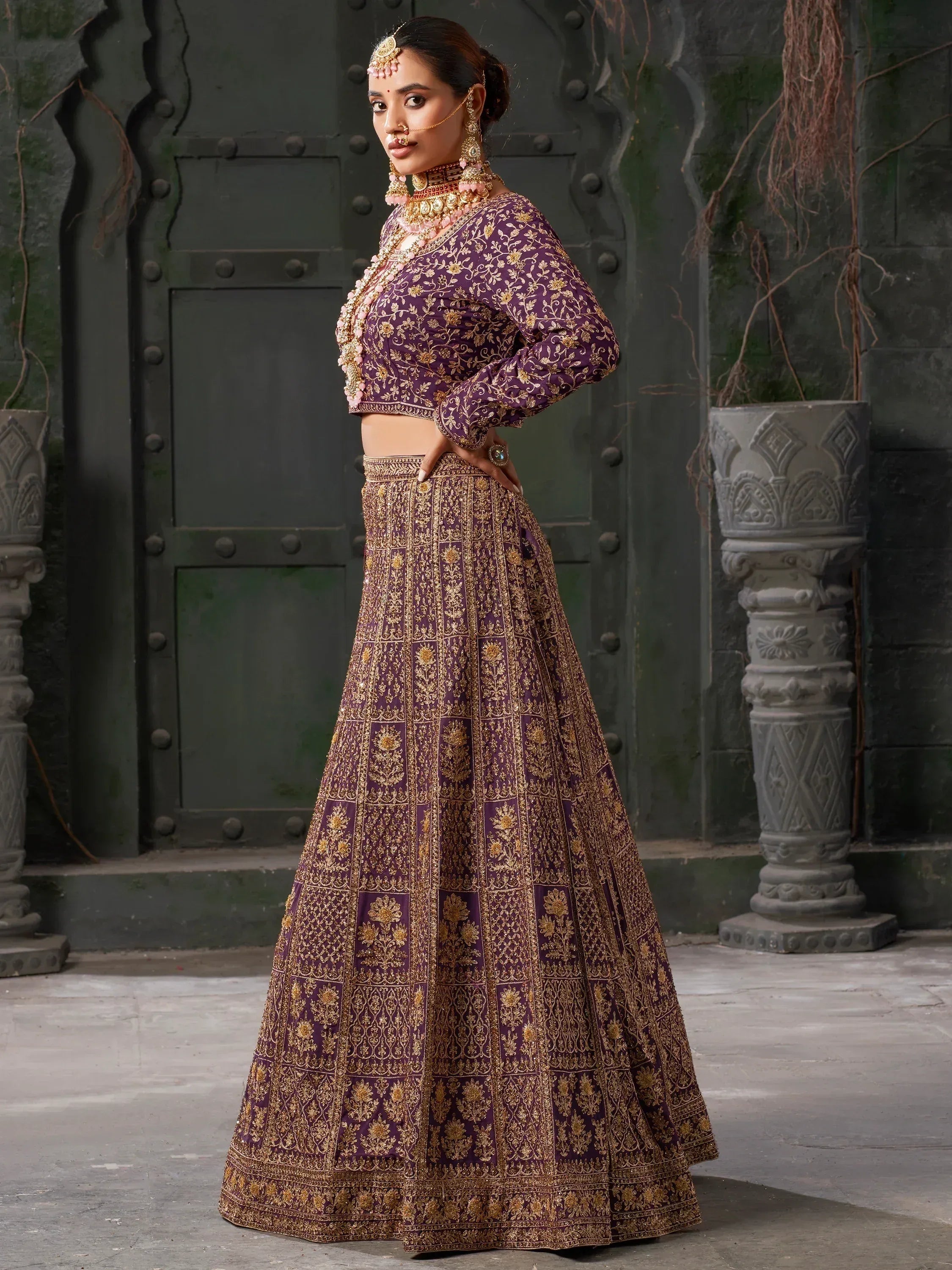 Purple and gold embroidered lehenga choli with traditional Indian jewelry, perfect for weddings and festivals.