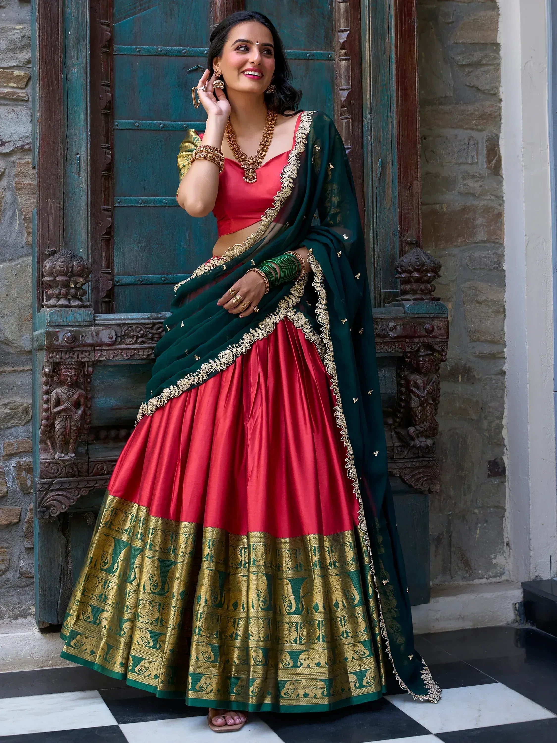 Red and green designer lehenga choli with gold elephant border, perfect for Indian ethnic wear occasions