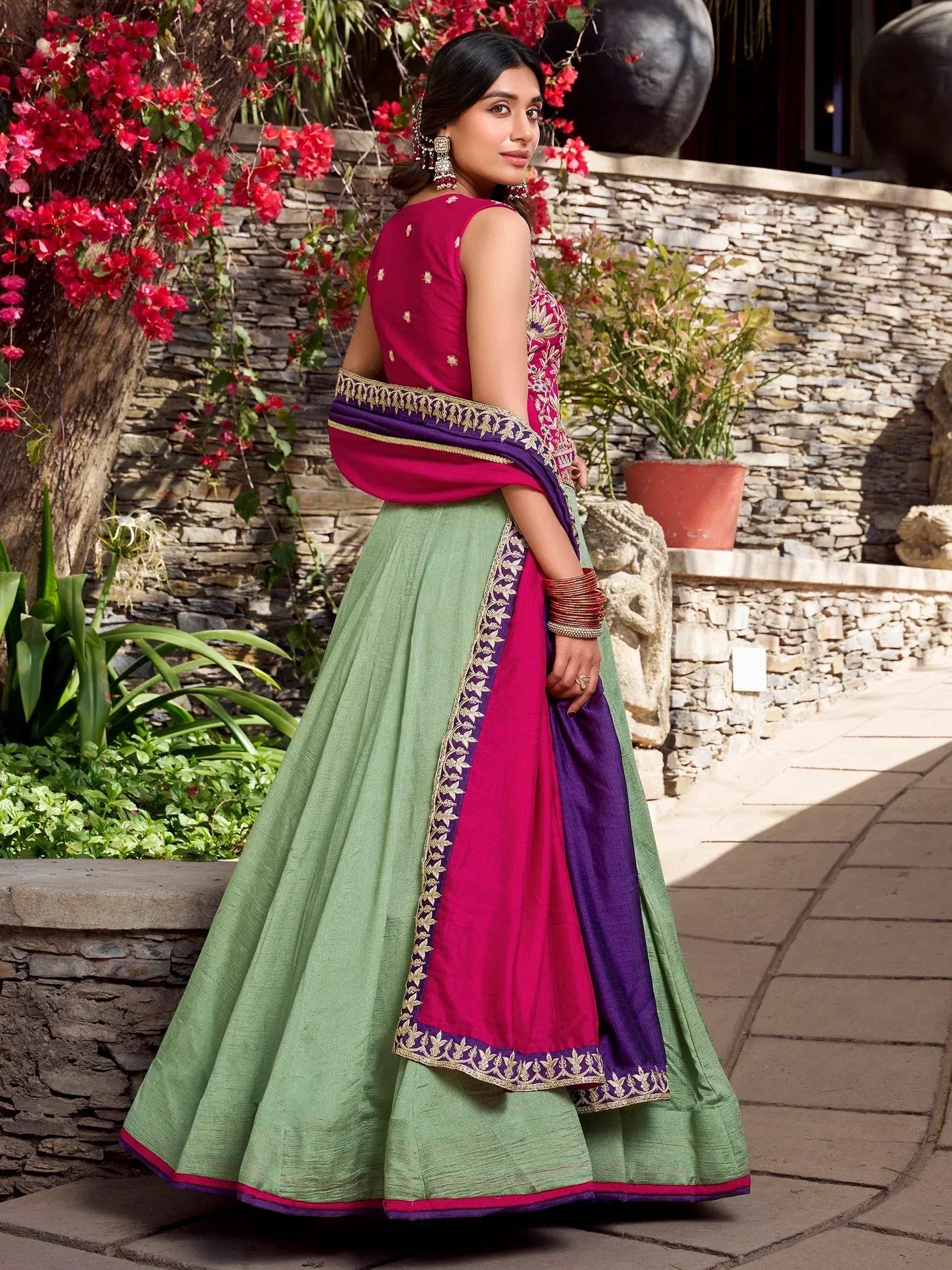 Woman in green and magenta lehenga choli with gold embroidery, perfect for Indian ethnic wear occasions