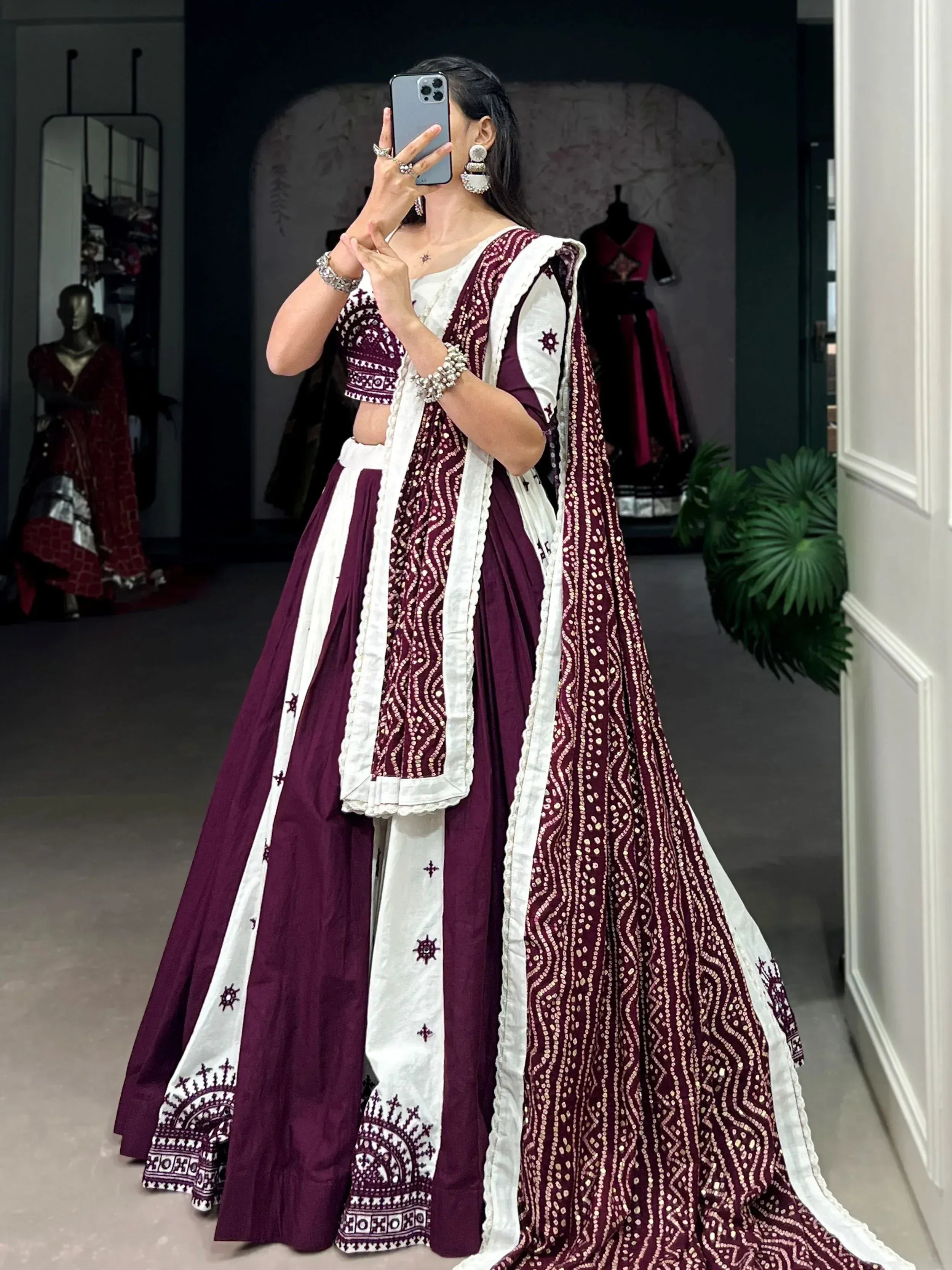 Woman in maroon and white embroidered lehenga choli taking mirror selfie, ethnic Indian wear