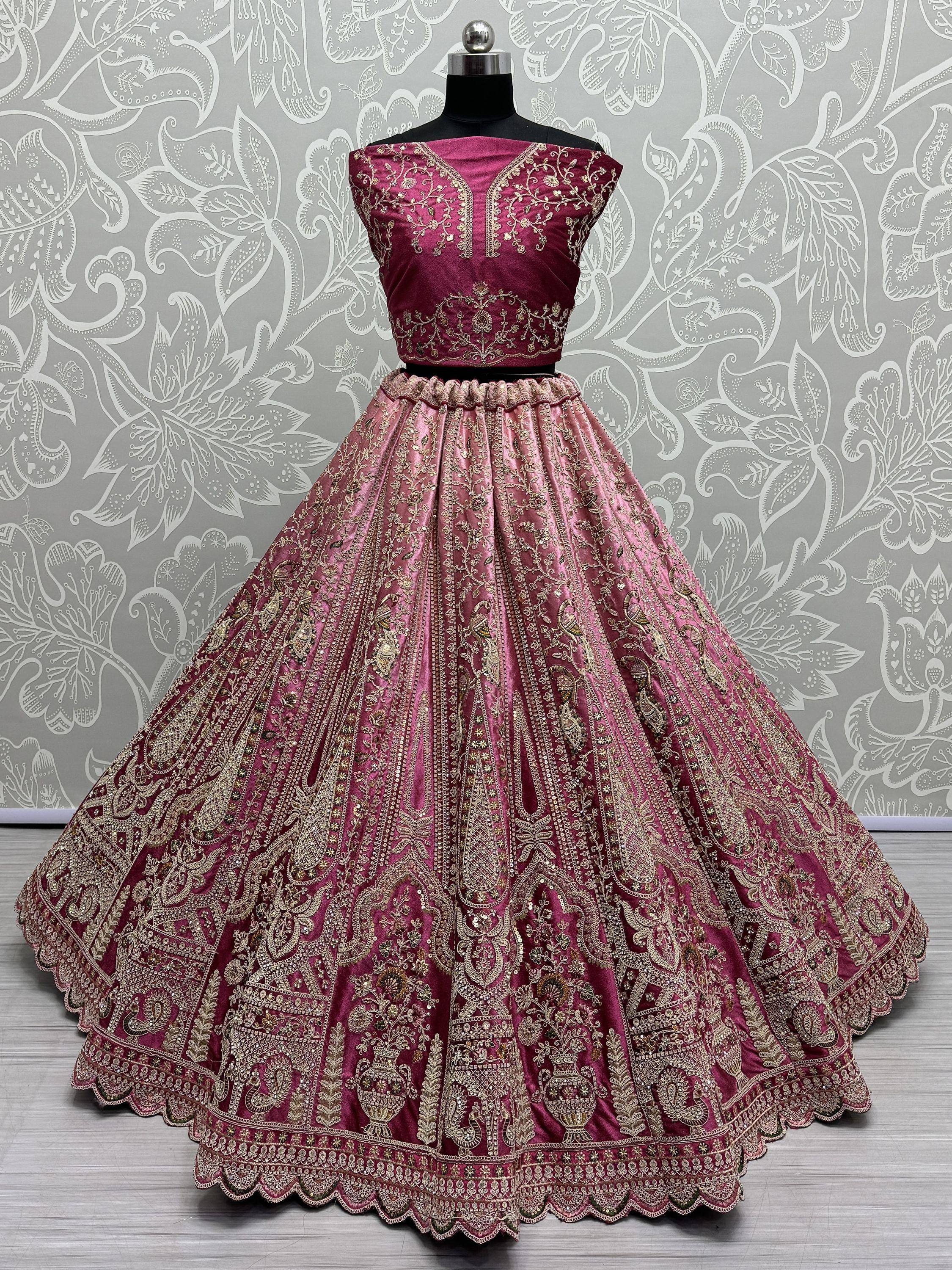 Pink embroidered lehenga choli with gold detailing, displayed on mannequin against floral backdrop
