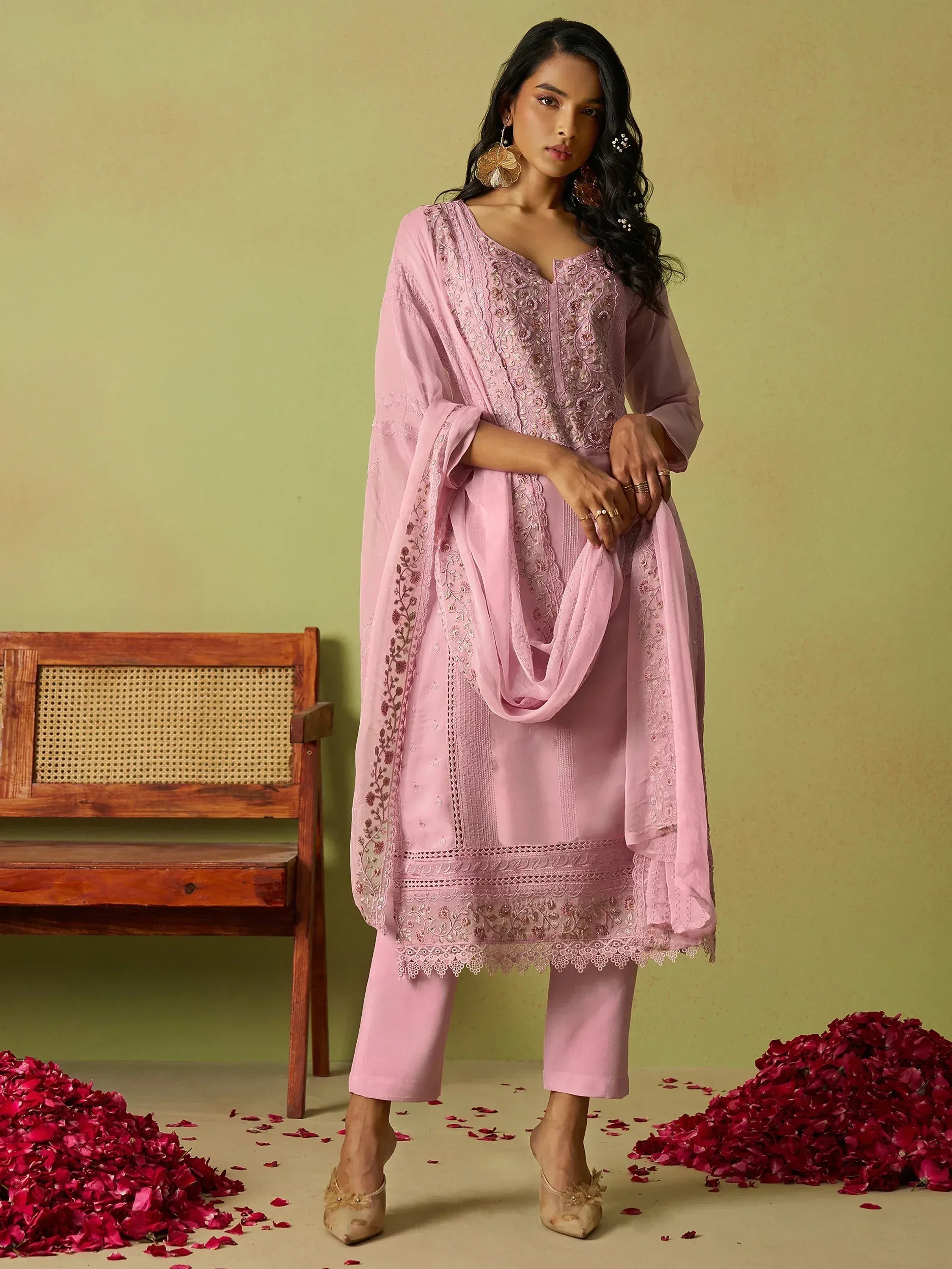 Pink embroidered salwar kameez with dupatta, floral detailing, and rose petals on floor