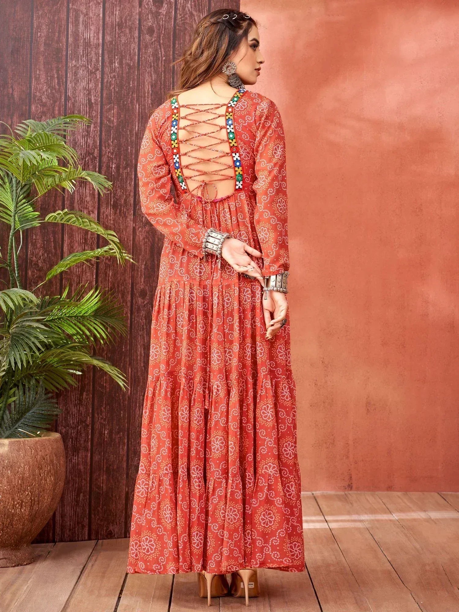 Orange floral print ethnic gown with back crisscross detailing and colorful embroidery, perfect for Indian occasions.