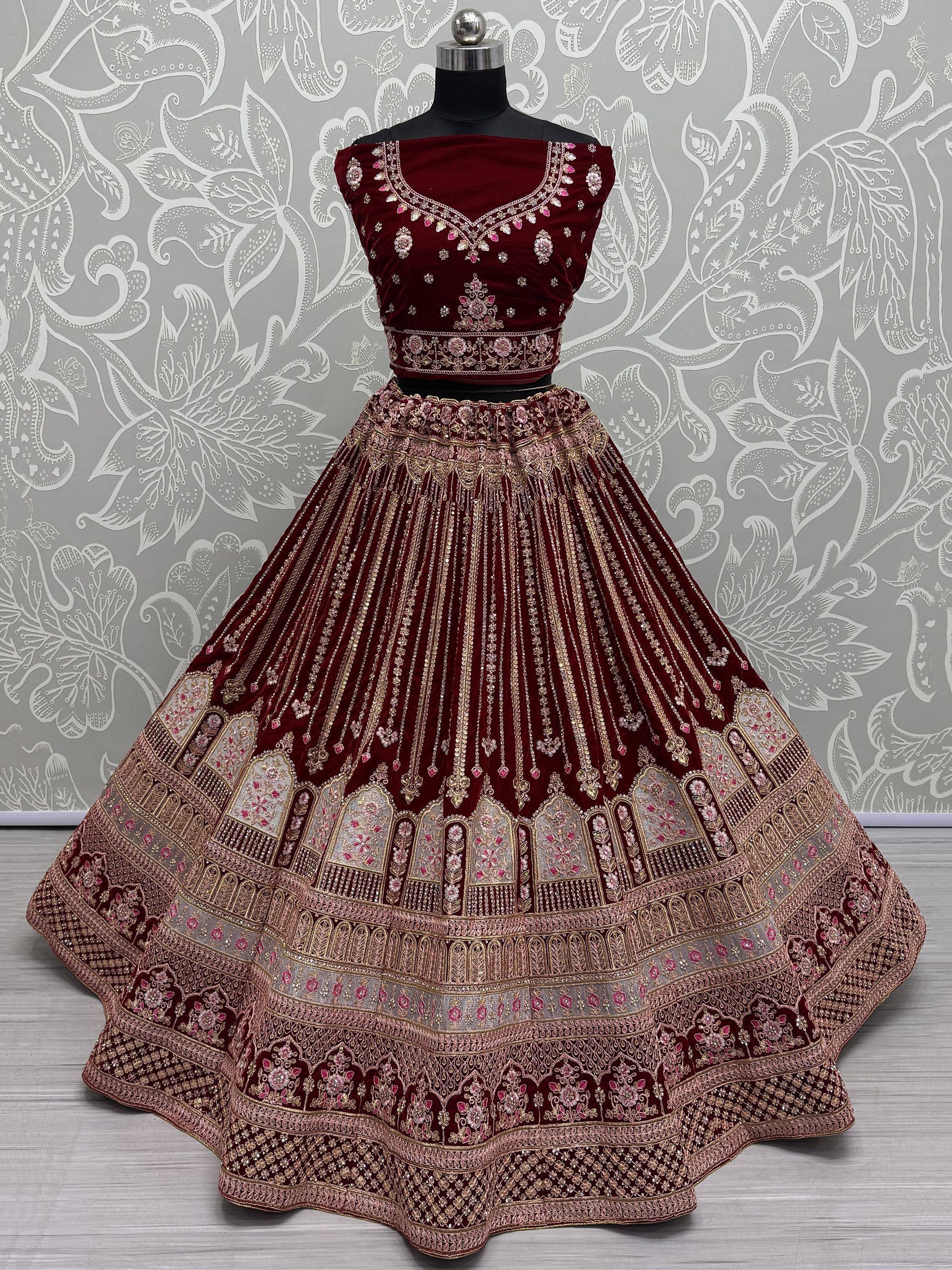 Maroon velvet lehenga choli with heavy gold and pink embroidery, perfect for Indian weddings and festive occasions.