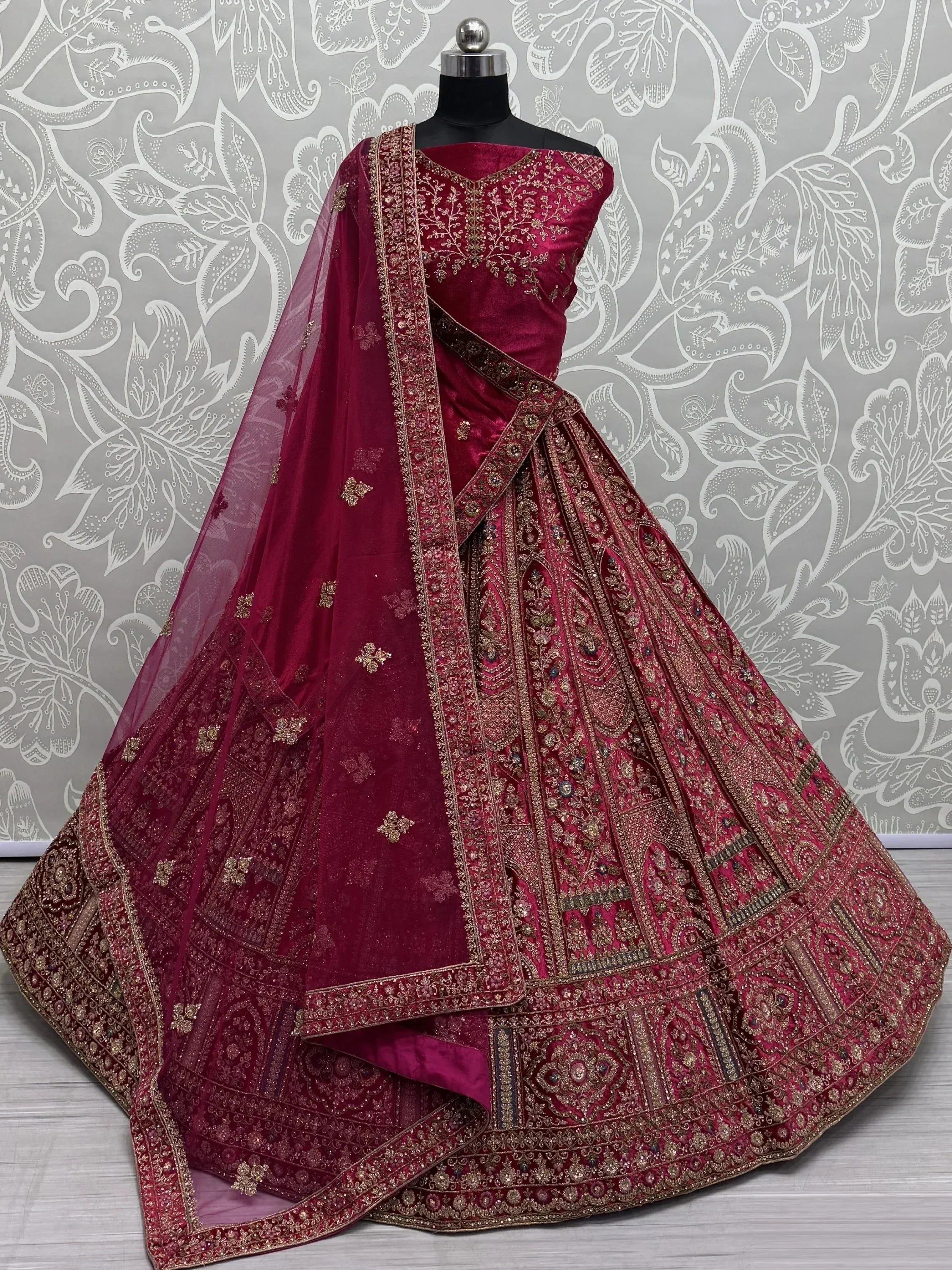 Luxury maroon velvet lehenga choli with gold embroidery and net dupatta, perfect for weddings and festive occasions.