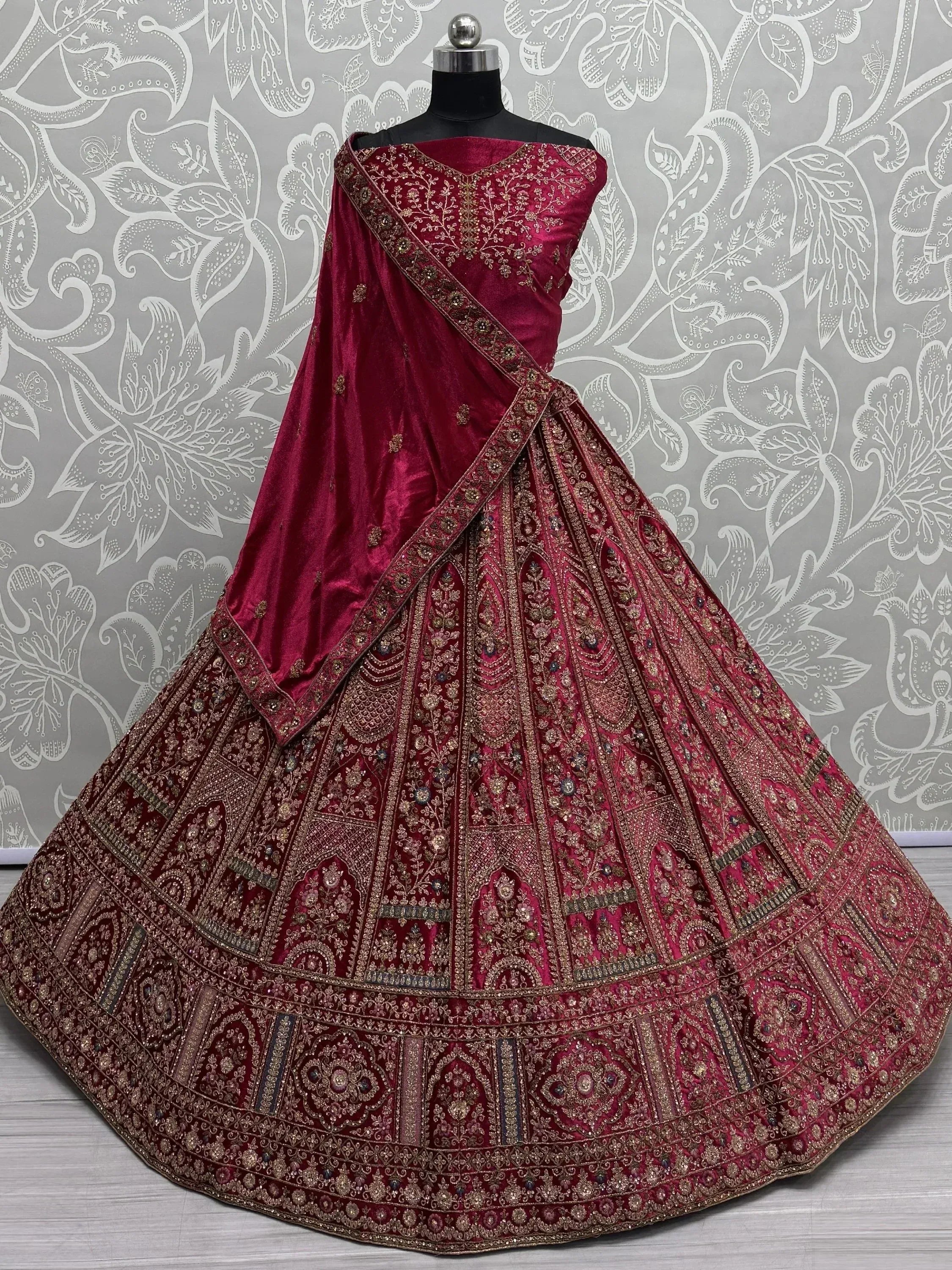 Burgundy velvet designer lehenga choli with heavy gold embroidery, perfect for Indian weddings and festive occasions.