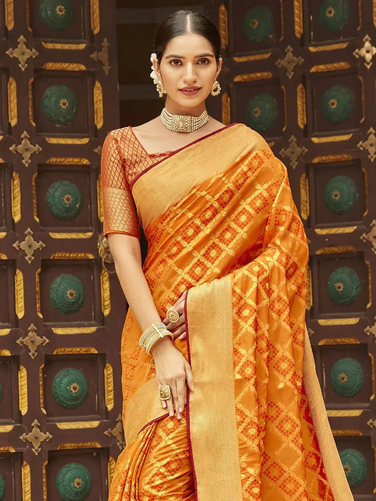 Orange designer saree with gold geometric patterns, paired with matching blouse and traditional jewelry