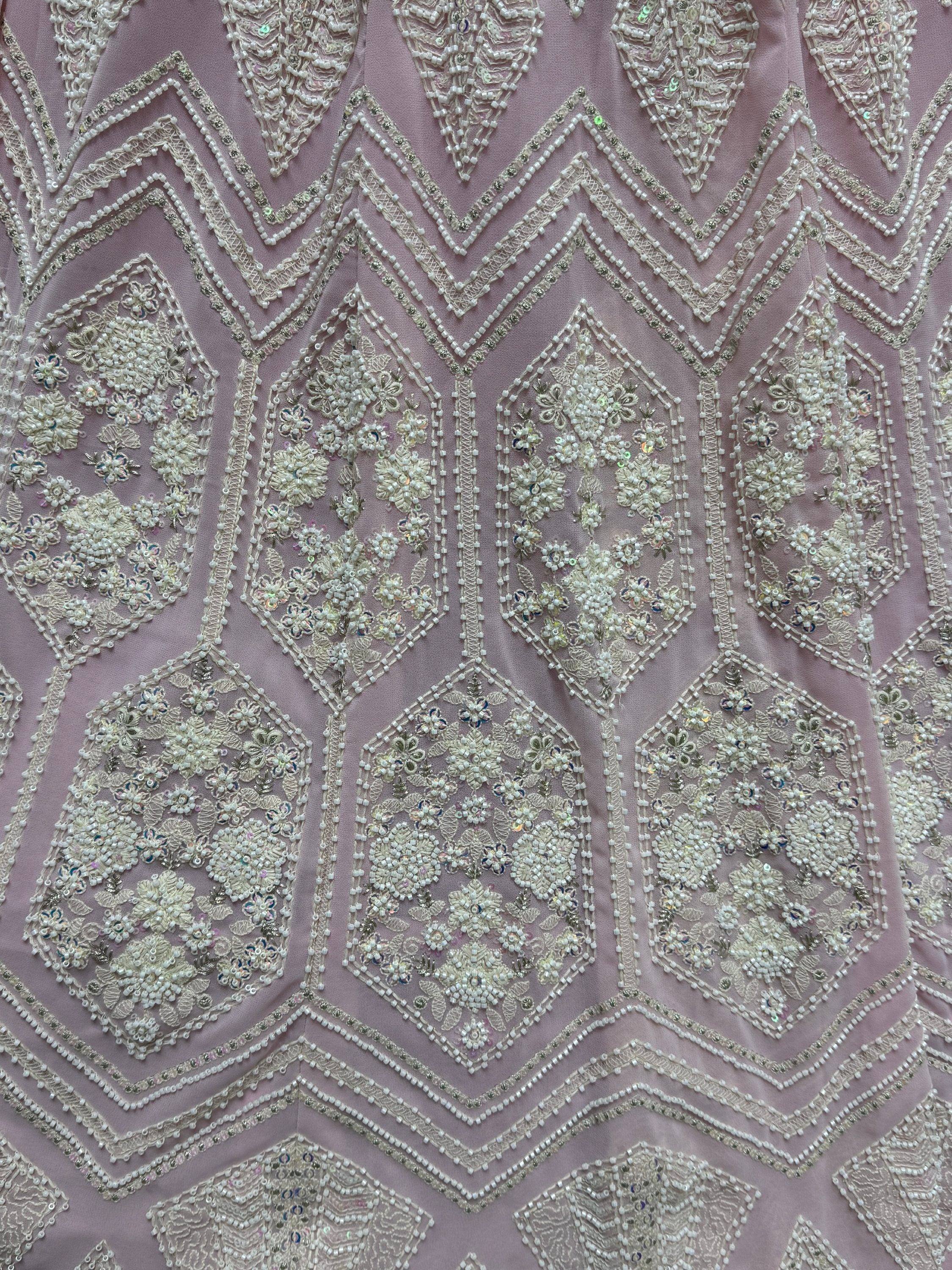 Pink ethnic wear with intricate white beadwork, floral embroidery, and sequin detailing for designer lehenga or gown.