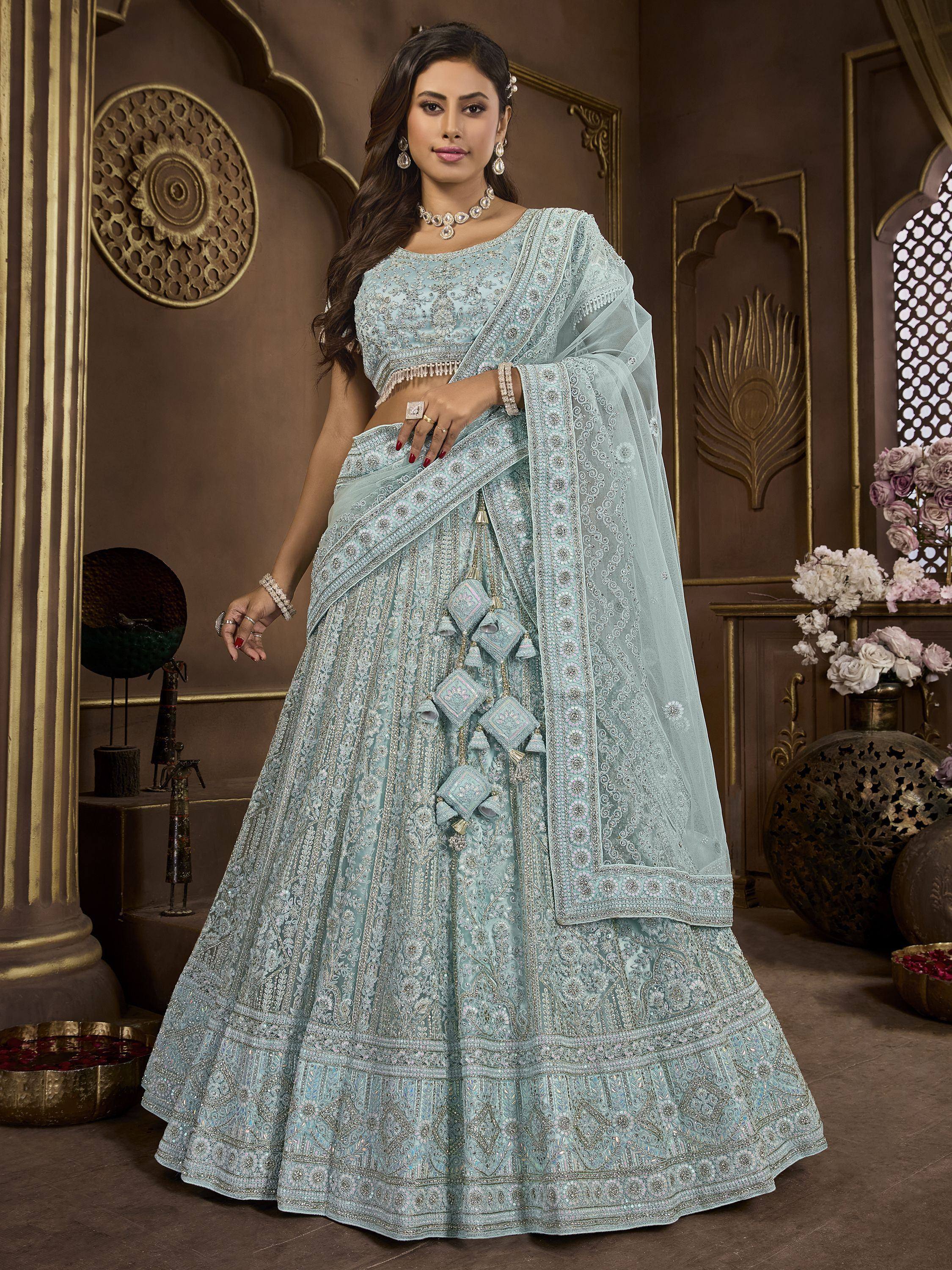 Elegant light blue designer lehenga choli with intricate embroidery and tassels, perfect for Indian weddings and festive occasions.