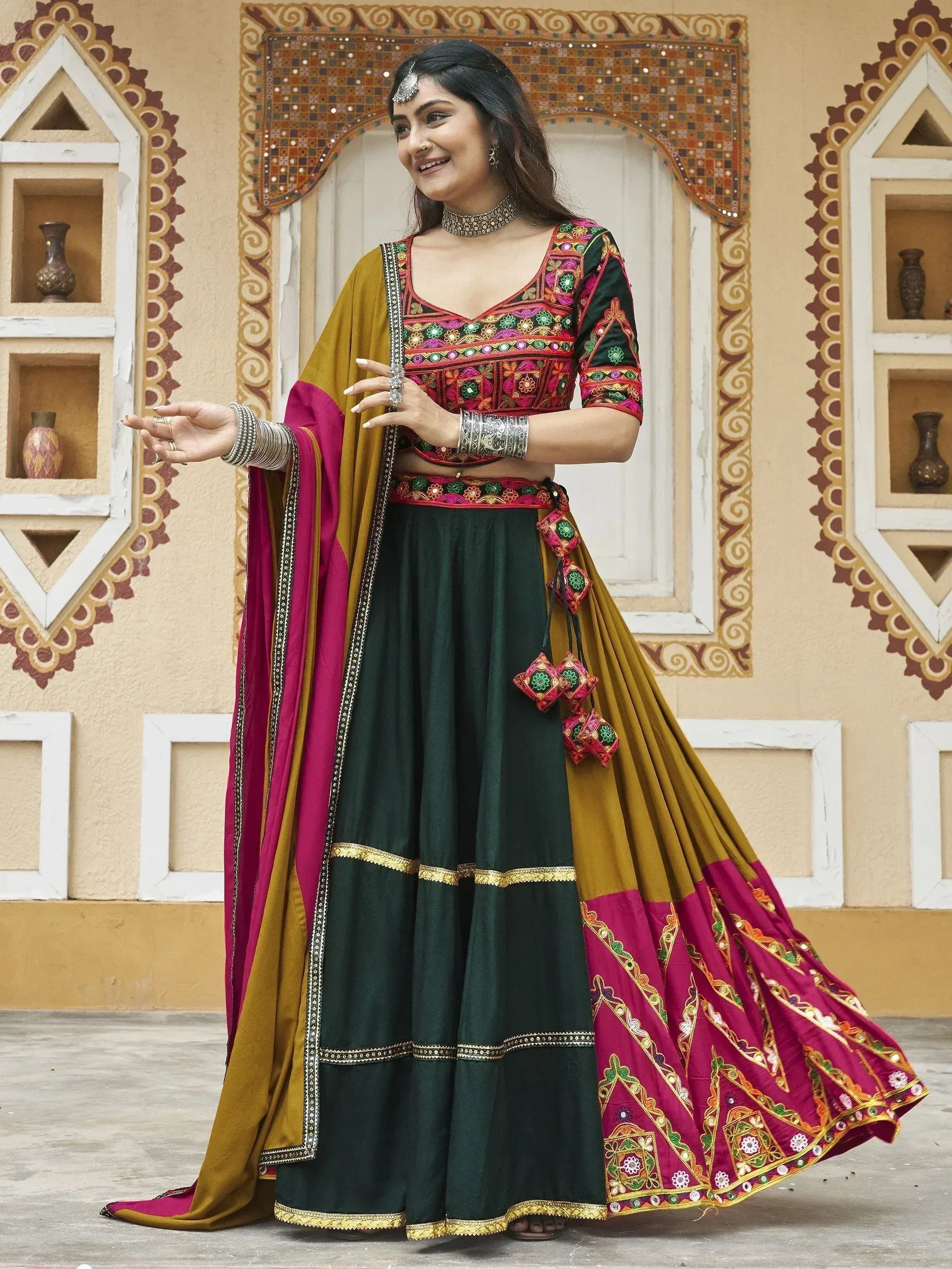 Woman in vibrant green and maroon embroidered lehenga choli with mirror work, traditional Indian ethnic wear