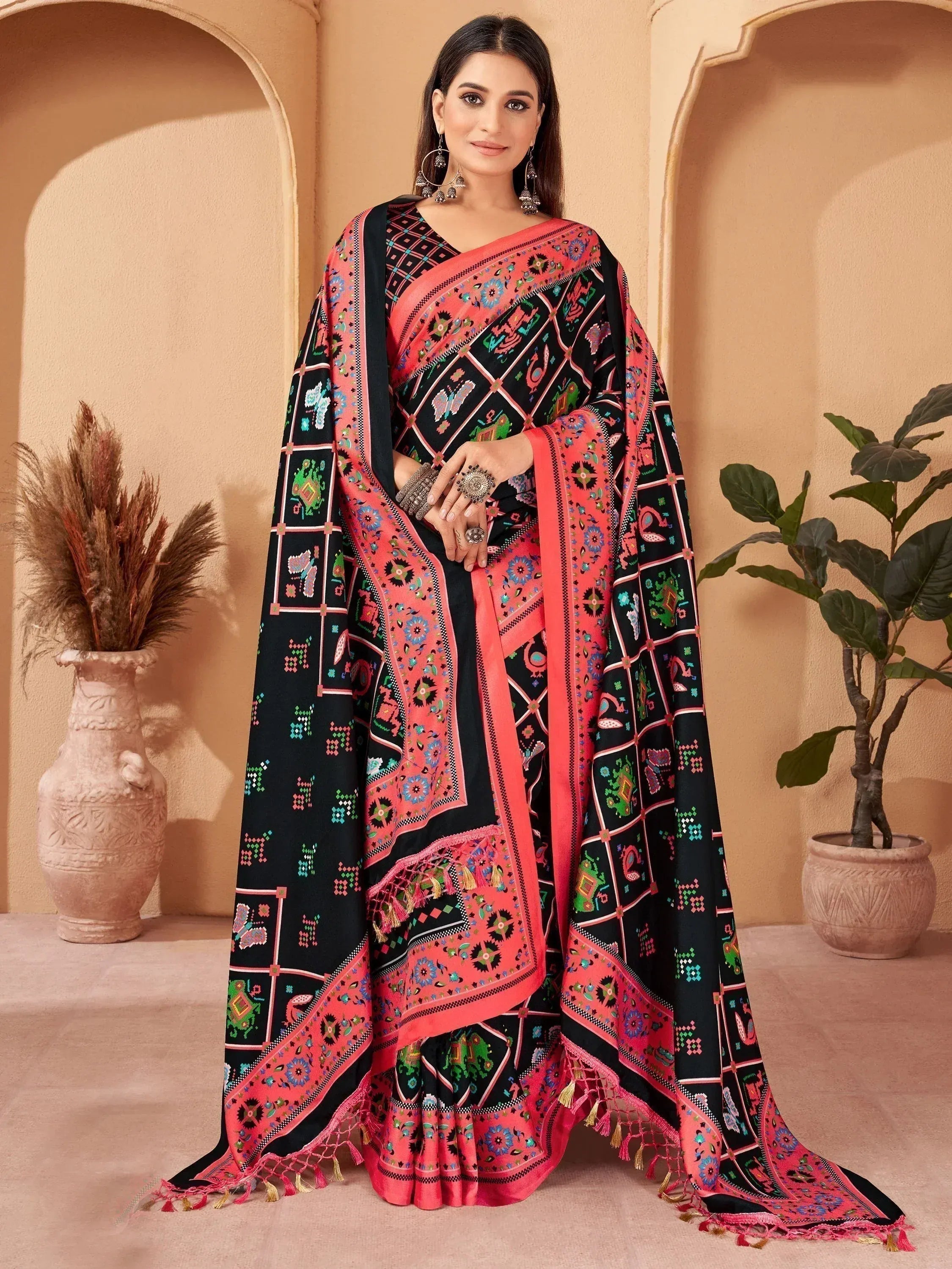 Black and coral printed ethnic saree with intricate patterns and tassels, styled with traditional jewelry