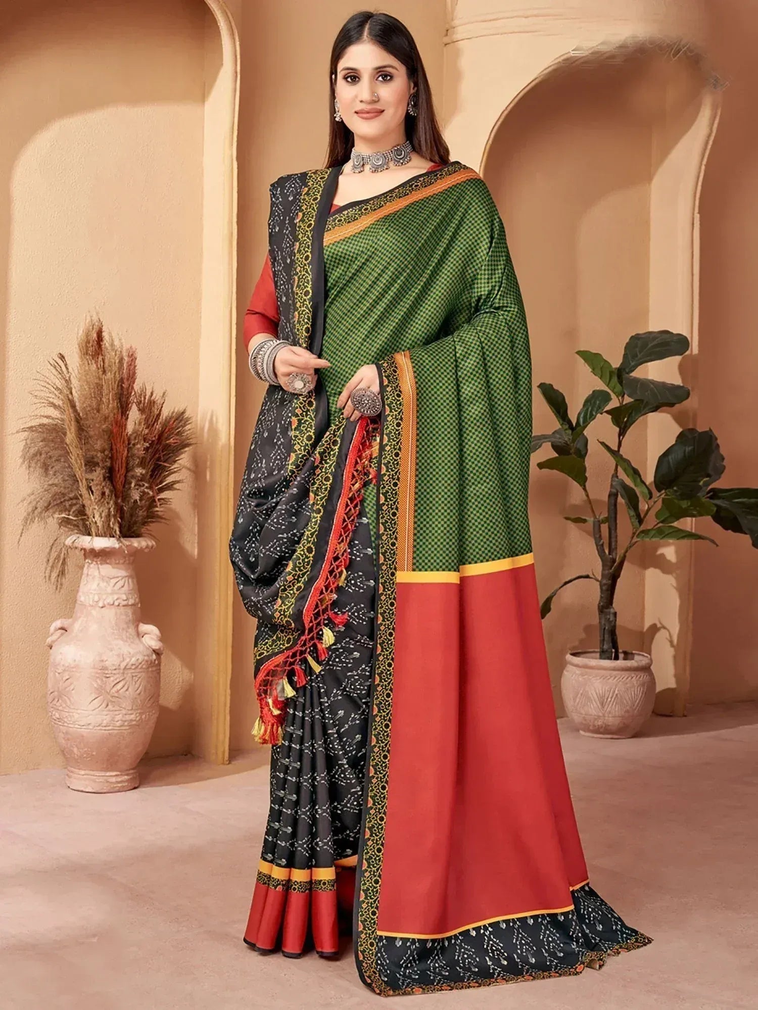 Green and red ethnic saree with black printed border and tassels, styled with traditional jewelry