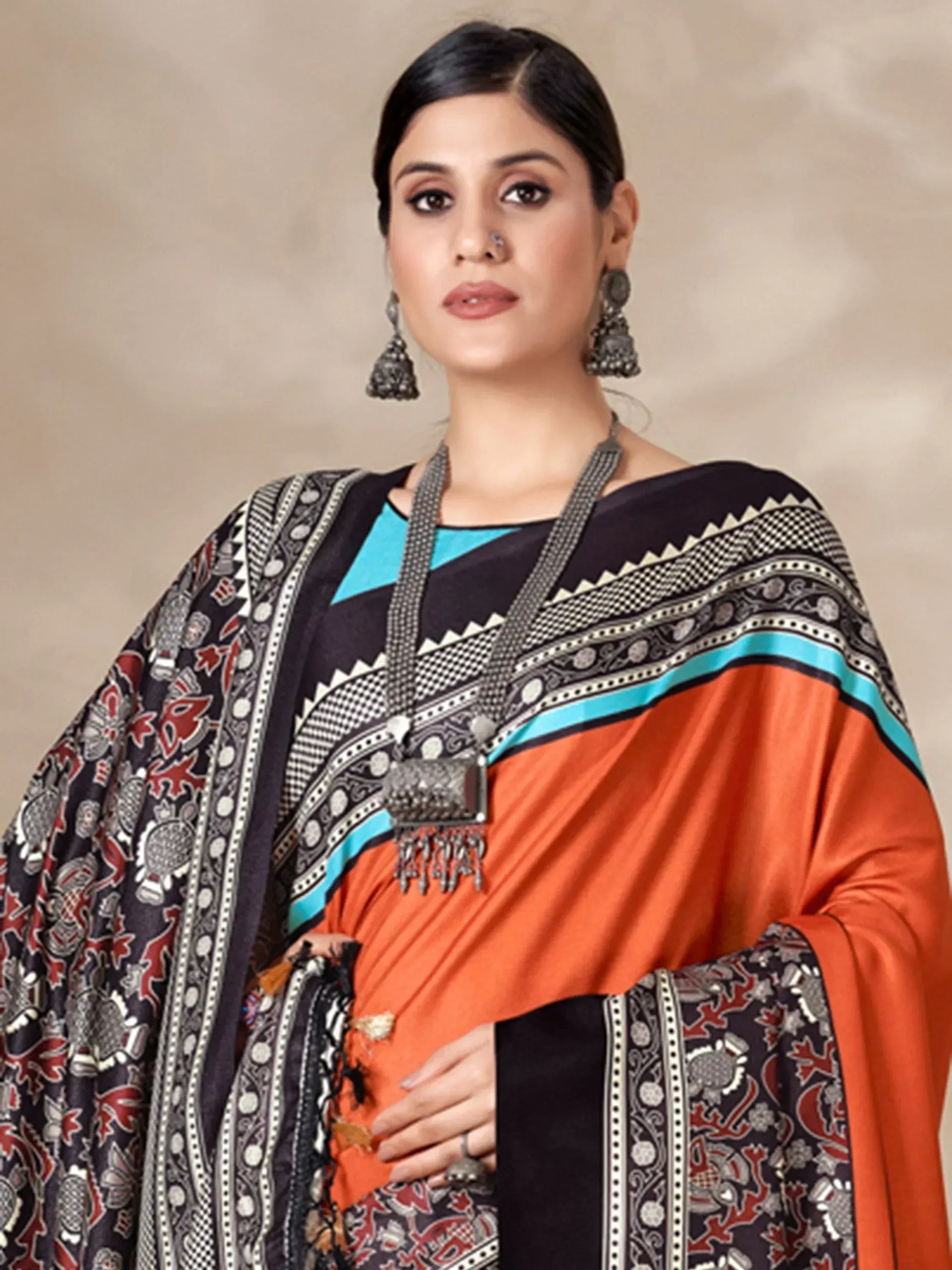 Woman in orange and black printed saree with turquoise blouse, ethnic jewelry, and traditional Indian attire