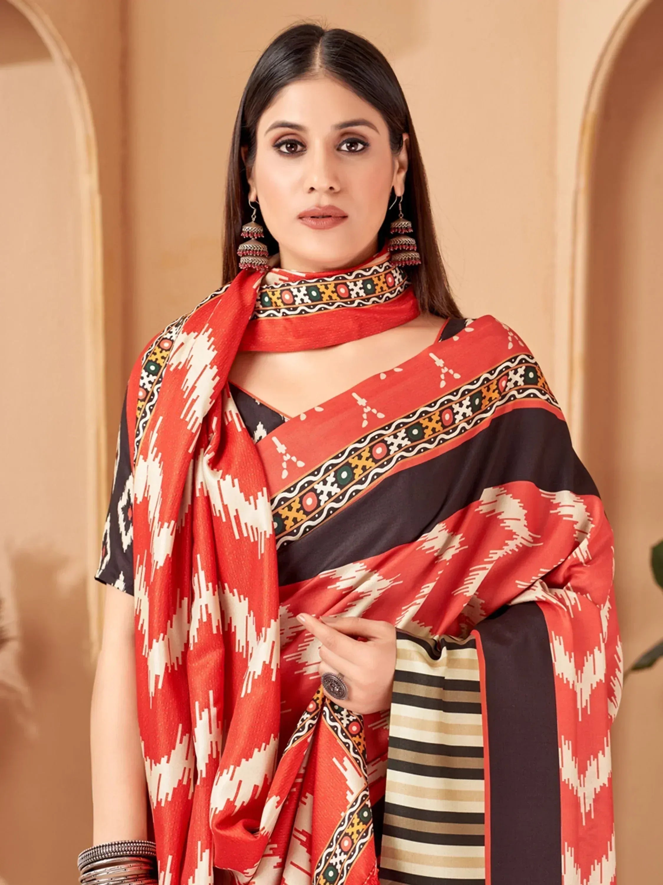 Woman in red and black printed ethnic saree with geometric patterns and traditional jewelry