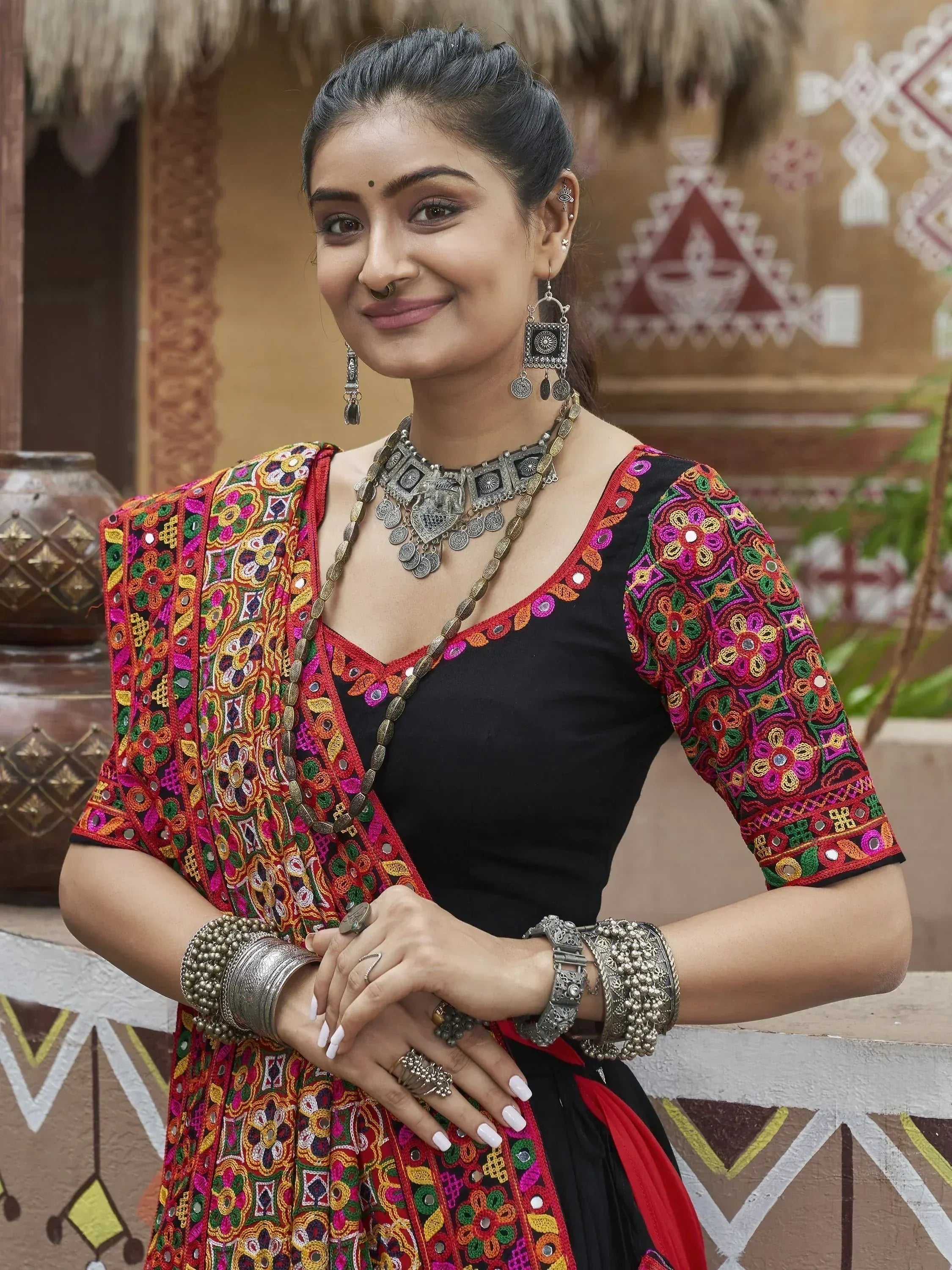 Woman in vibrant embroidered Indian ethnic wear with mirror work, traditional jewelry, and nose ring