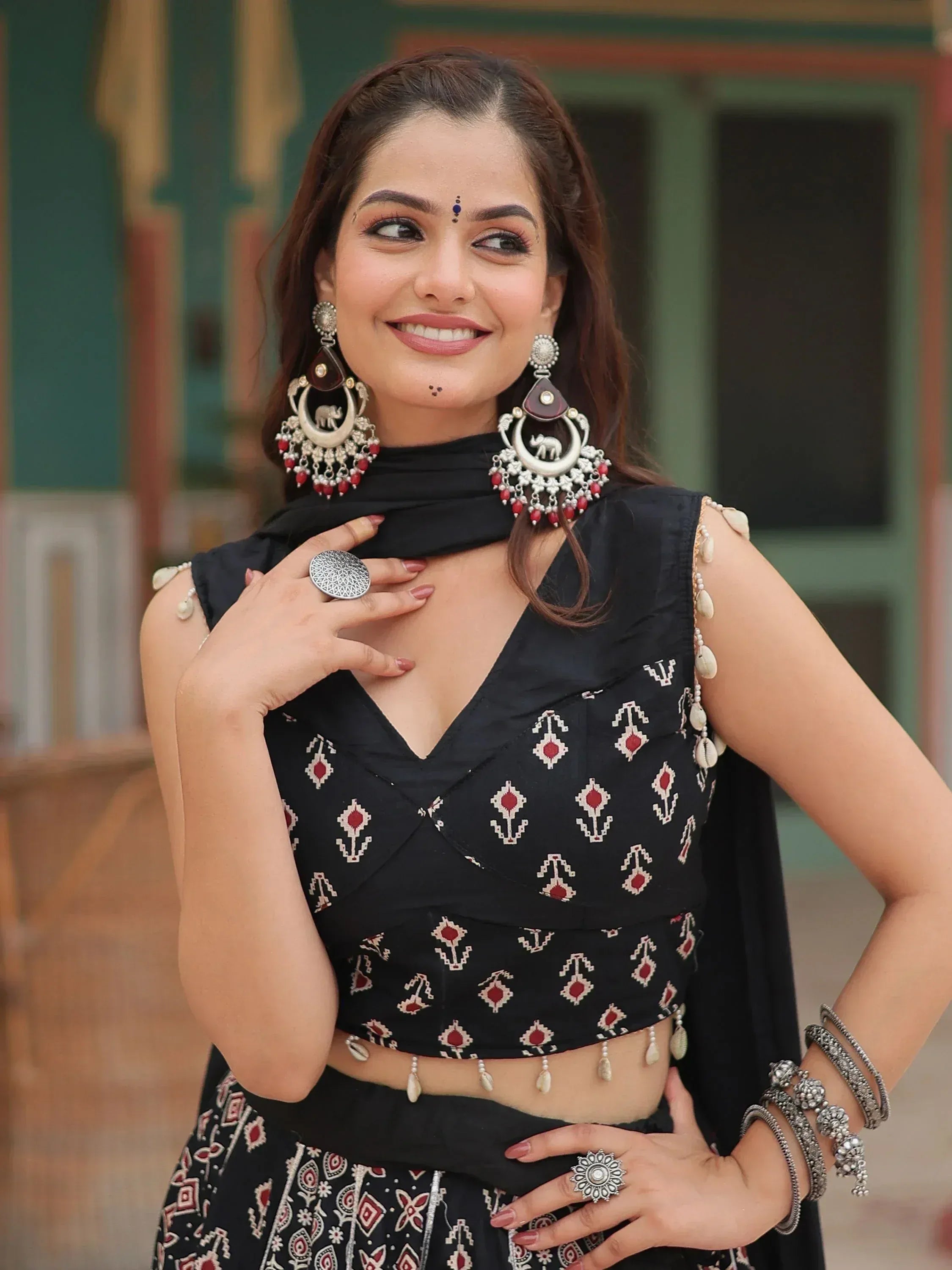 Woman in black ethnic crop top with red white print, elephant earrings, and traditional jewelry